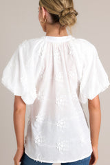 Back view of this White top with v-neckline, button front, embroidered detailing, and elastic cuffed puff sleeves.