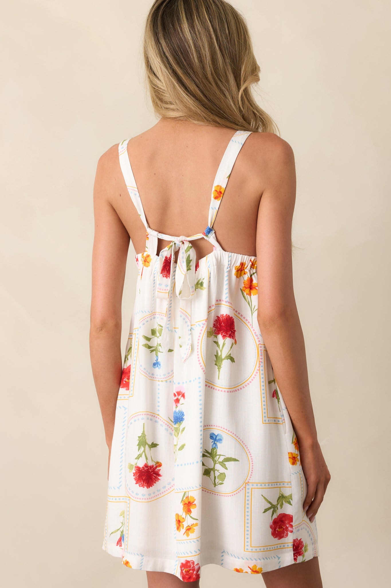 A view from behind of the ivory dress, featuring a back elastic waist insert and a self-tie closure.