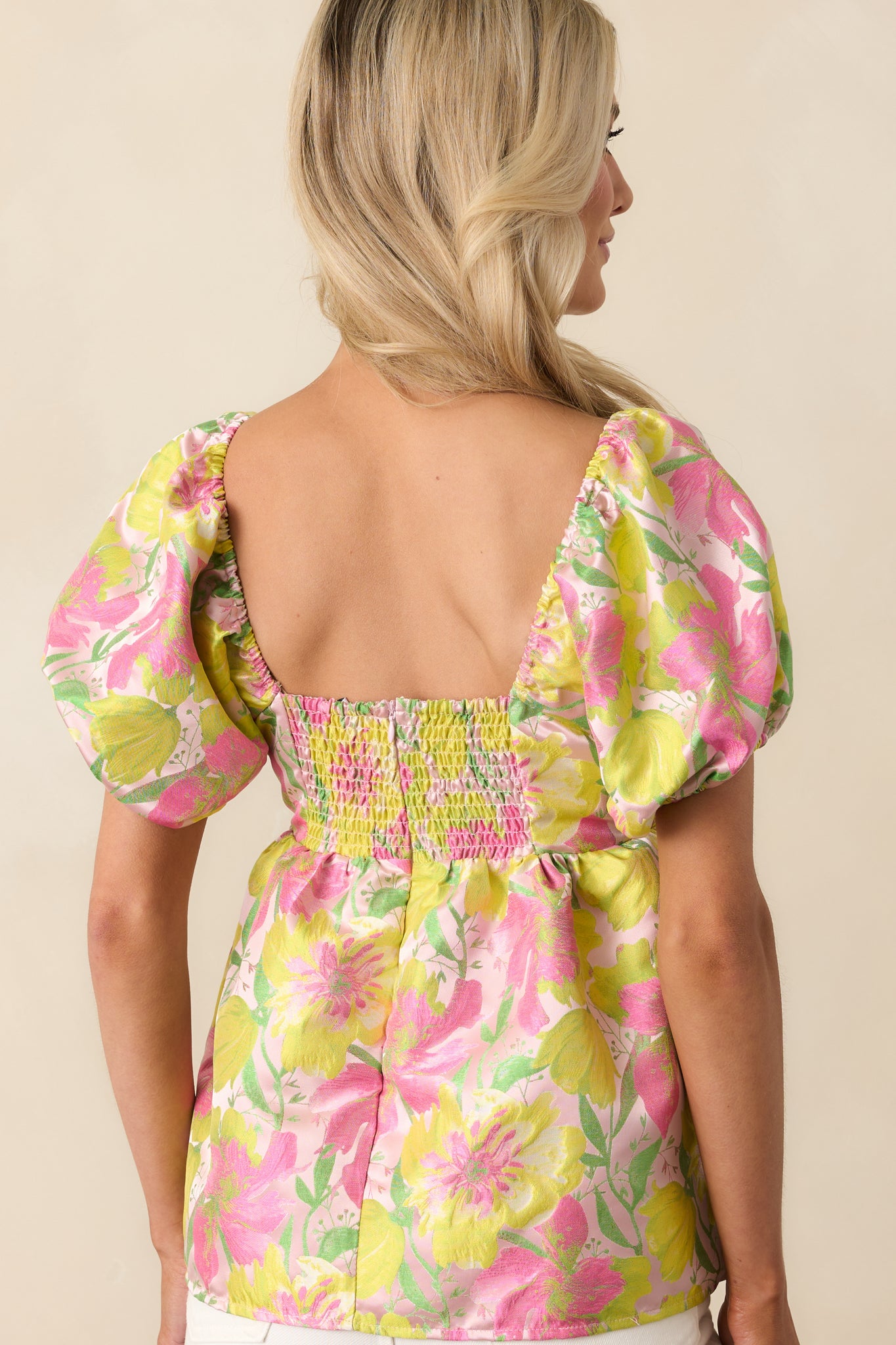 A view from behind of the light pink top featuring the smocked panel and discrete zipper closure.