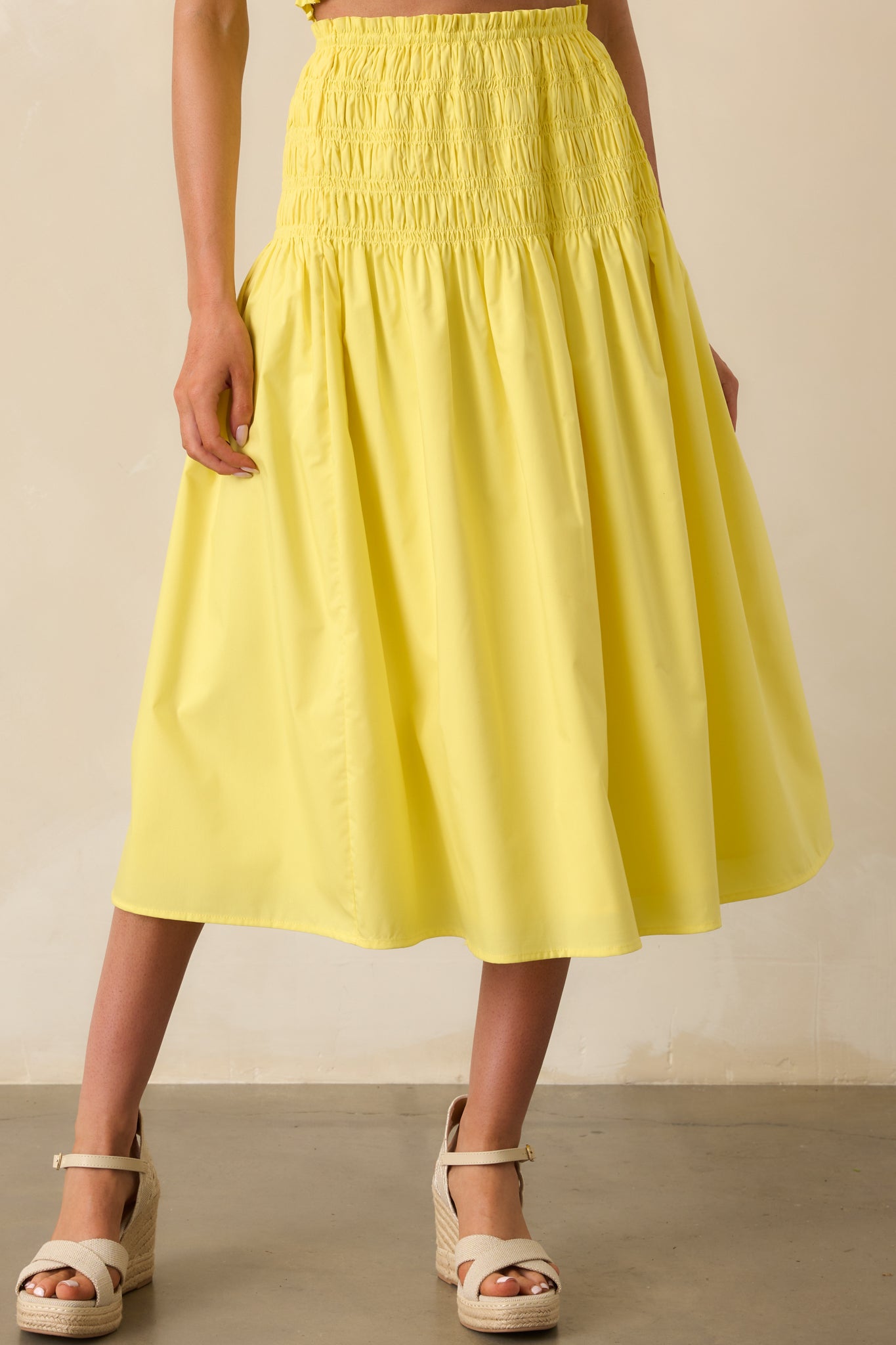 A close-up cropped view of the yellow skirt’s fabric, capturing the smooth, lightweight material.