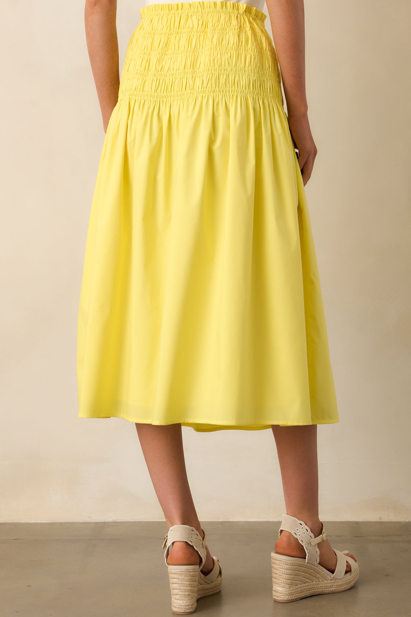 A back view of the yellow midi skirt, showing the gathered smocked waistband and flowy back hem.