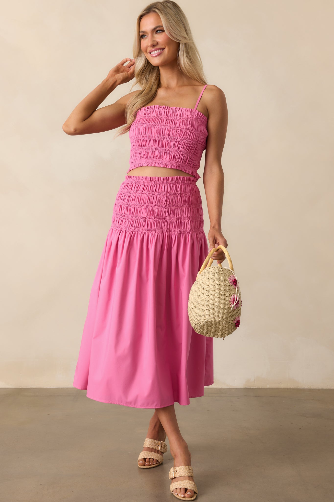 Full-length image of a pink midi skirt featuring a smocked drop waistband and ruffle trim detail.