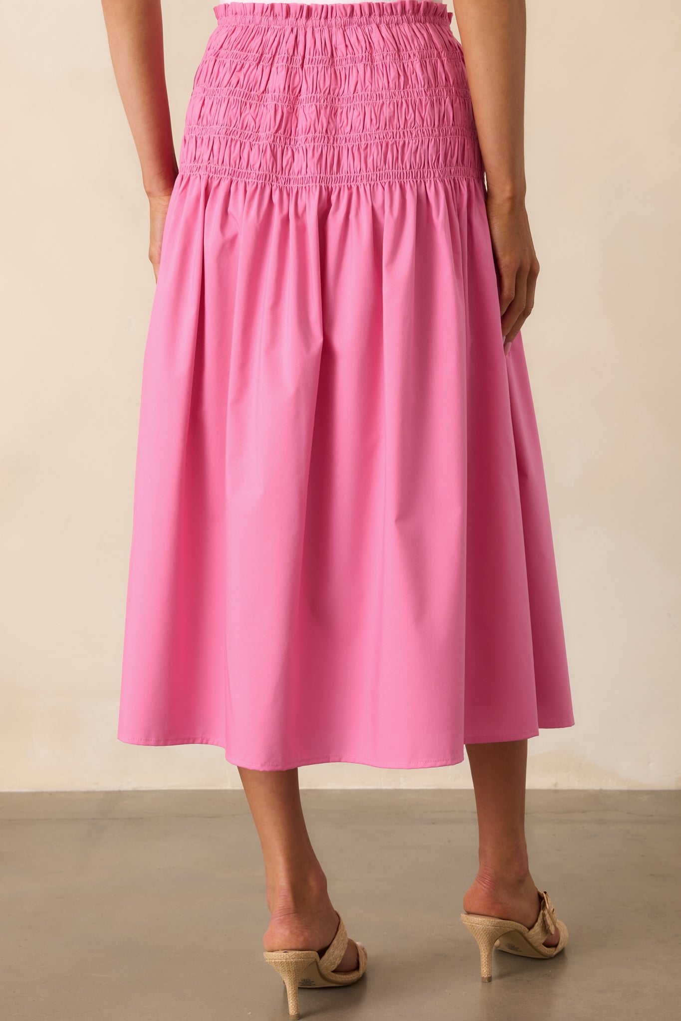 A view from behind of the midi skirt, highlighting the full smocked drop waist and smooth flow of the skirt’s back panel.