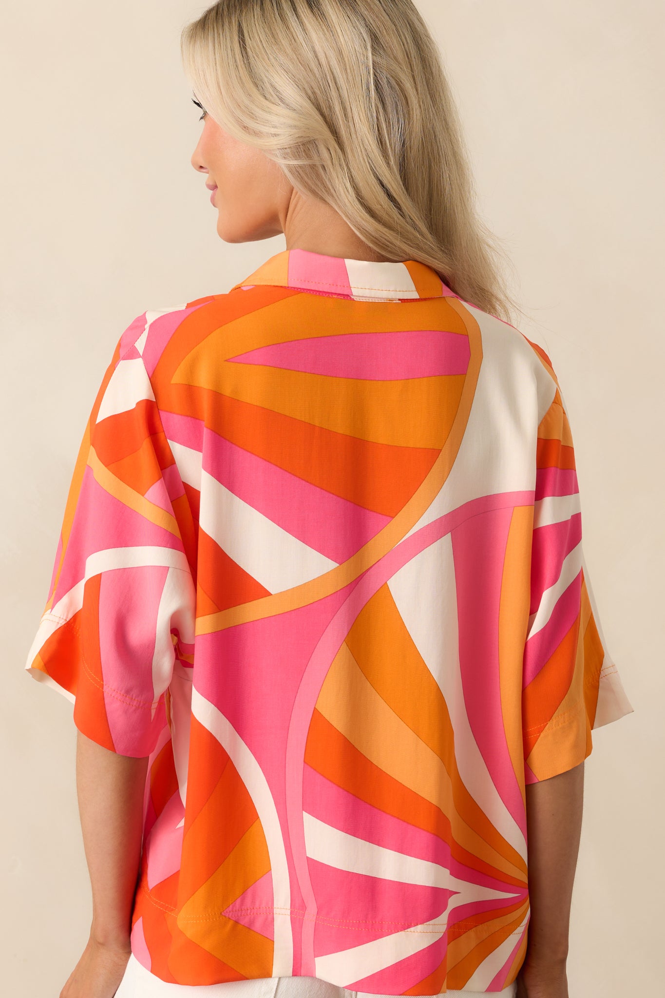 Back view of the orange top displaying the geometric pattern continuation and loose, oversized shape.