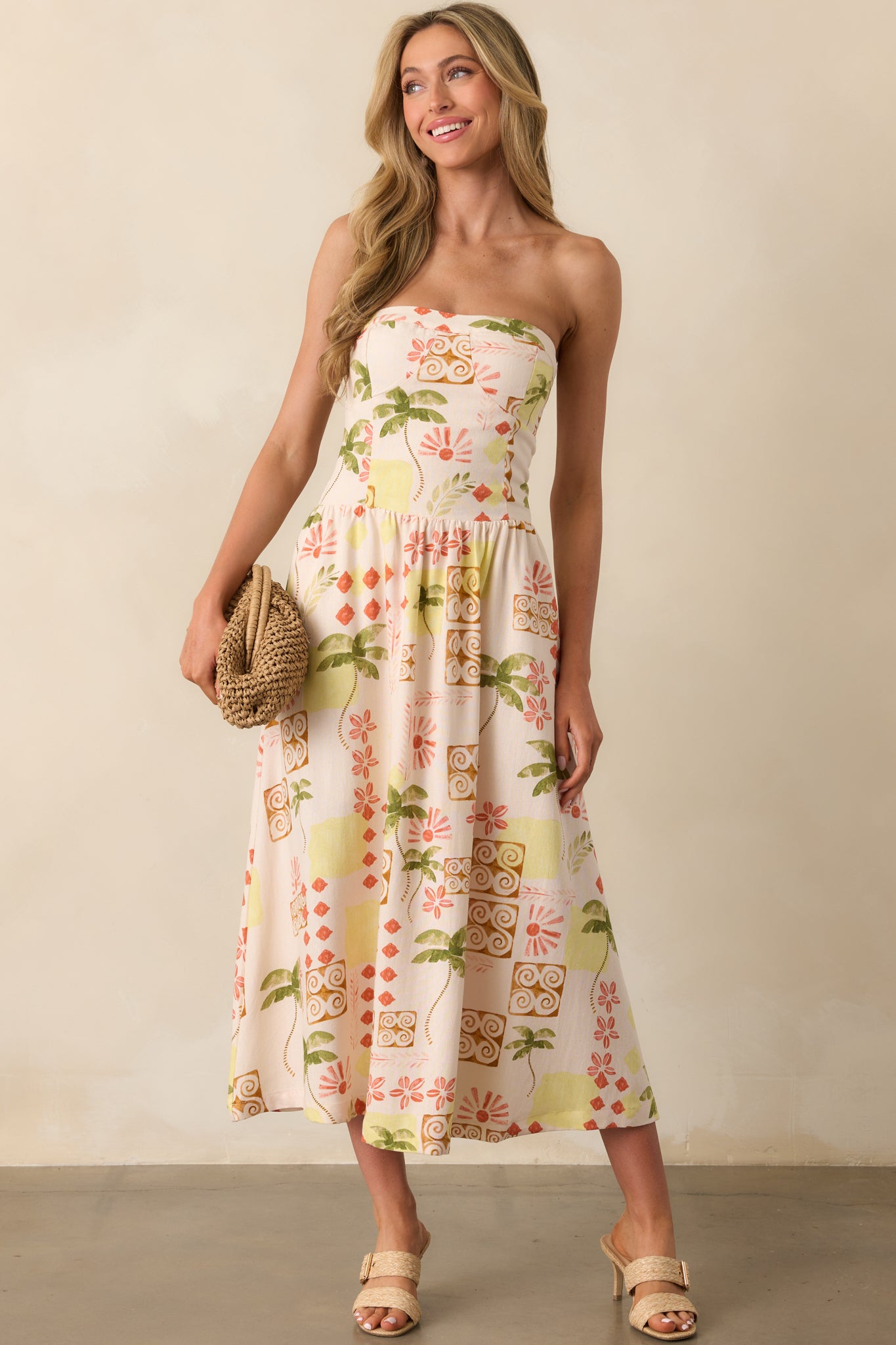 Full-length view of a beige strapless dress with a colorful tropical print, featuring a bustier-style neckline and a flowy skirt.