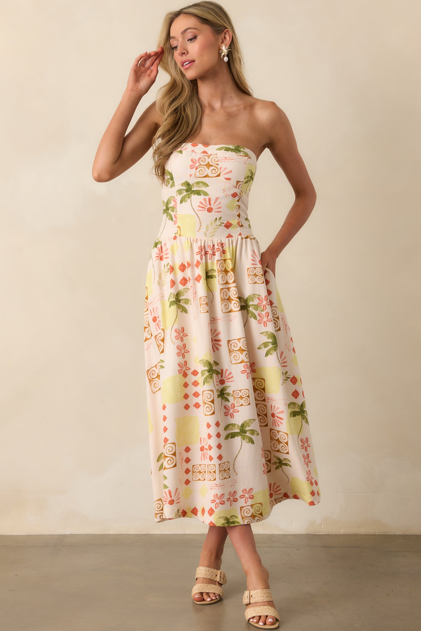 Beige strapless dress in full view, emphasizing the lively print and subtle shaping through the bodice and waist.