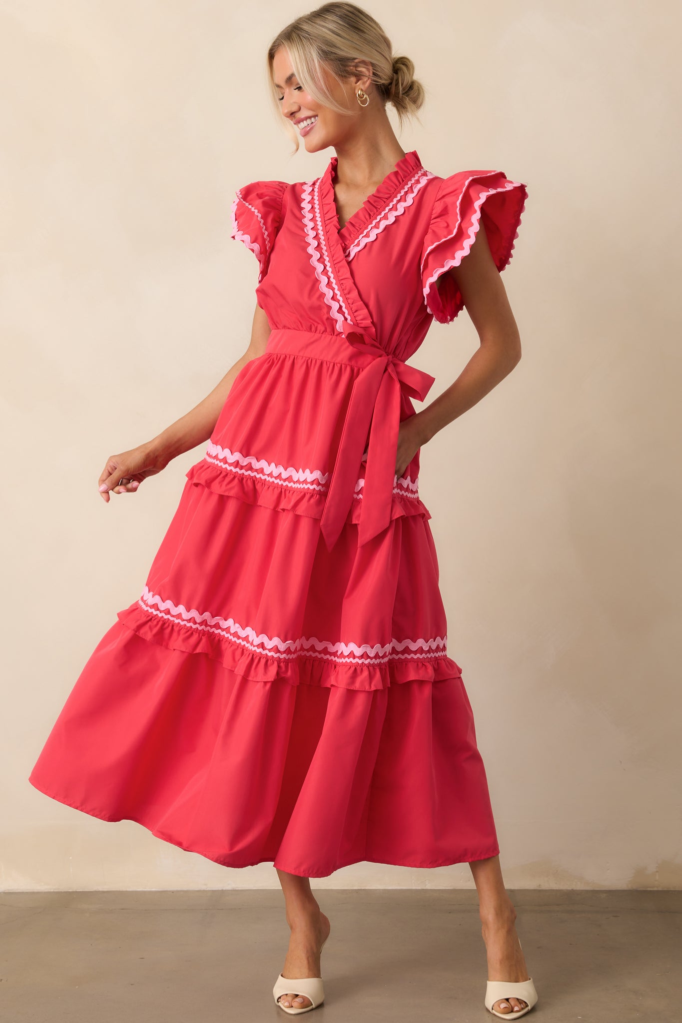 Full-length image of a red dress with a ruffle neckline, snap button closure, and a tiered skirt with decorative trim.
