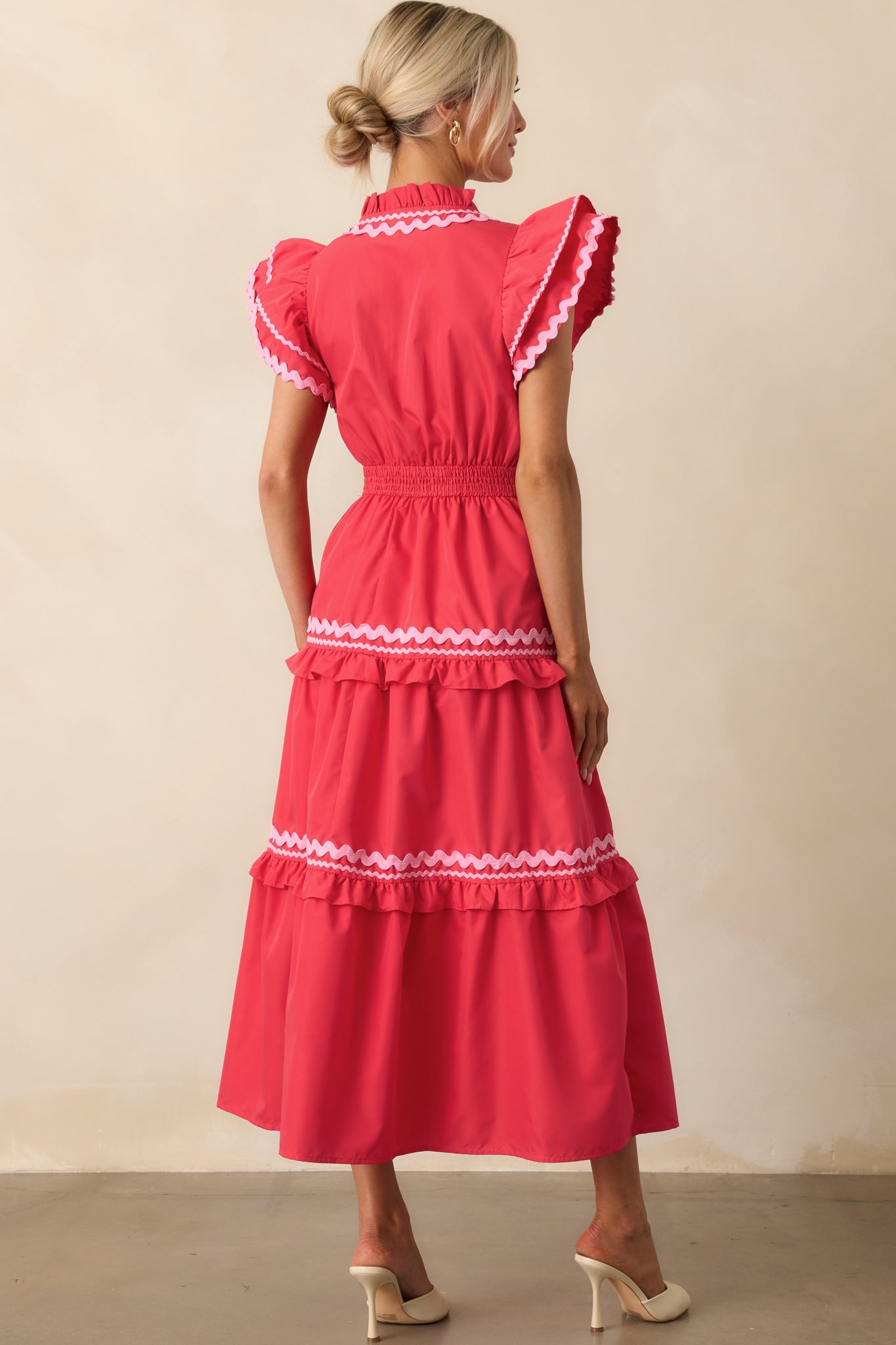 A view from behind of the red maxi dress, focusing on the smocked back waist panel and the continuation of the ruffle-tiered skirt.