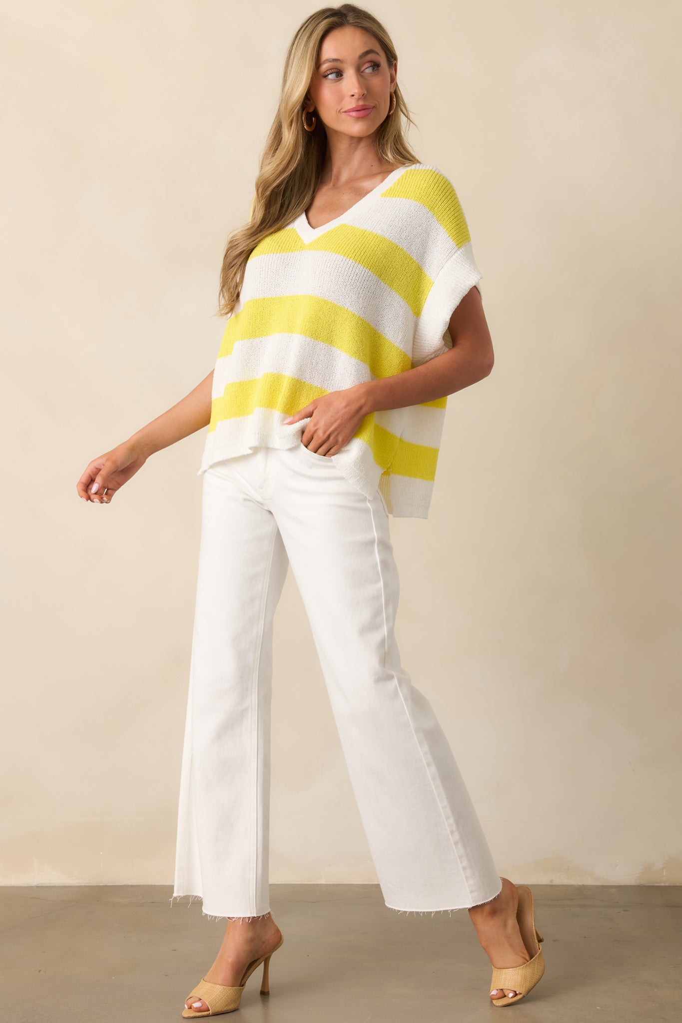 Full-length photo highlighting the loose knit texture and side hem vent slits of the striped top.