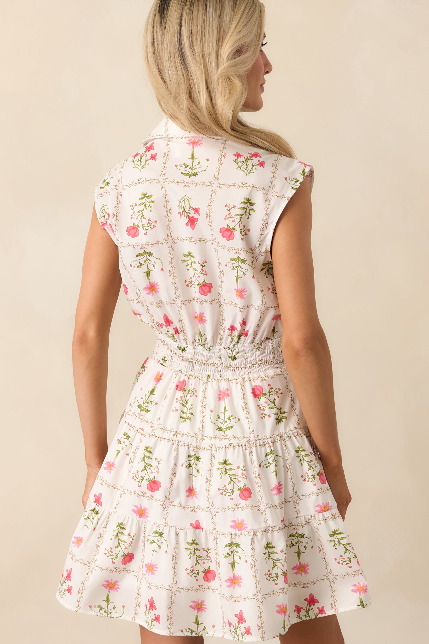 A view from behind of the ivory mini dress, featuring the smocked back waist panel and tiered skirt design