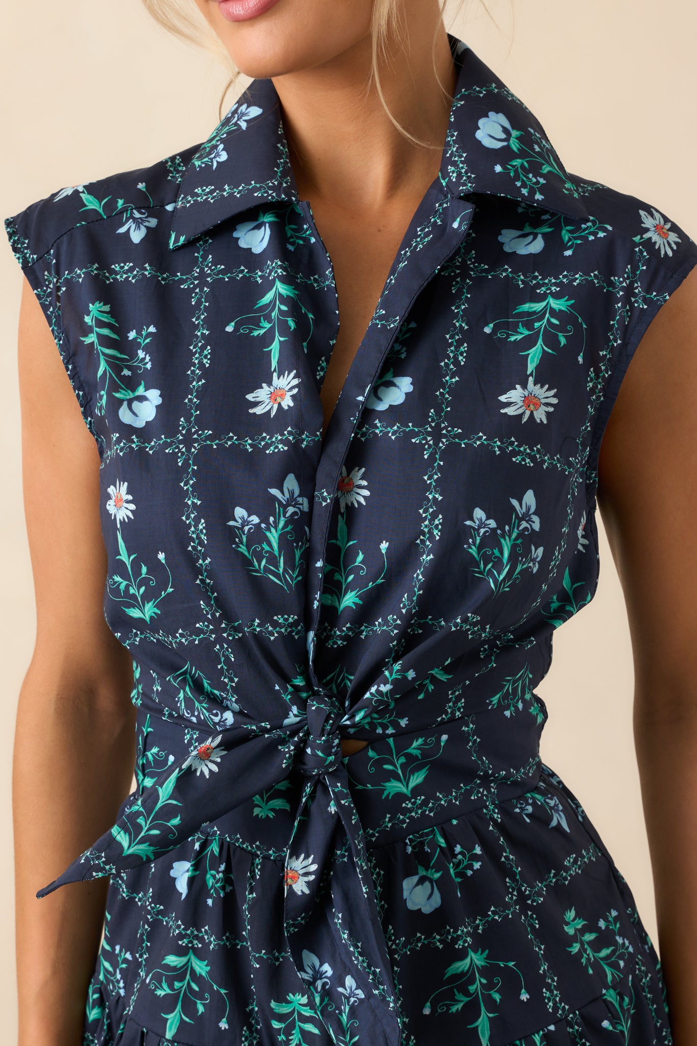 Close-up photo displaying the light blue floral print and textured fabric of the navy mini dress near the button placket.