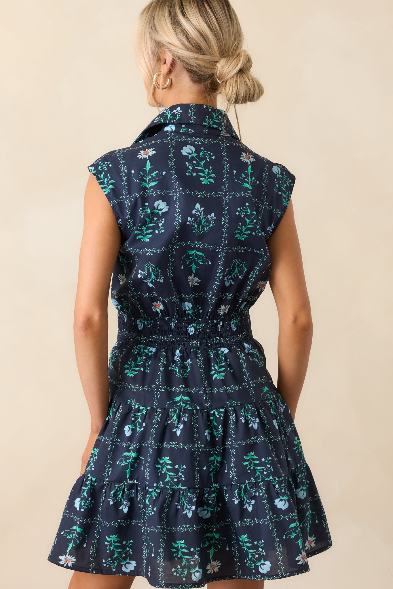 Close-up photo displaying the light blue floral print and textured fabric of the navy mini dress near the button placket.