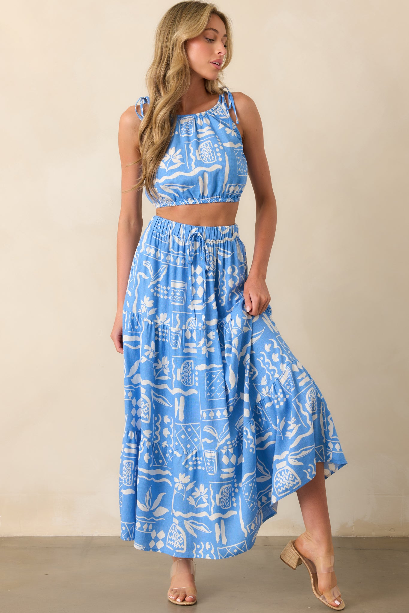 Front view of a blue maxi skirt featuring a white tropical print and tiered skirt design.
