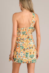 A back view of this dress that features an asymmetrical neckline, a knot detail, a smocked back insert, a discrete zipper, a self-tie wrap feature, and a unique eye-catching print.