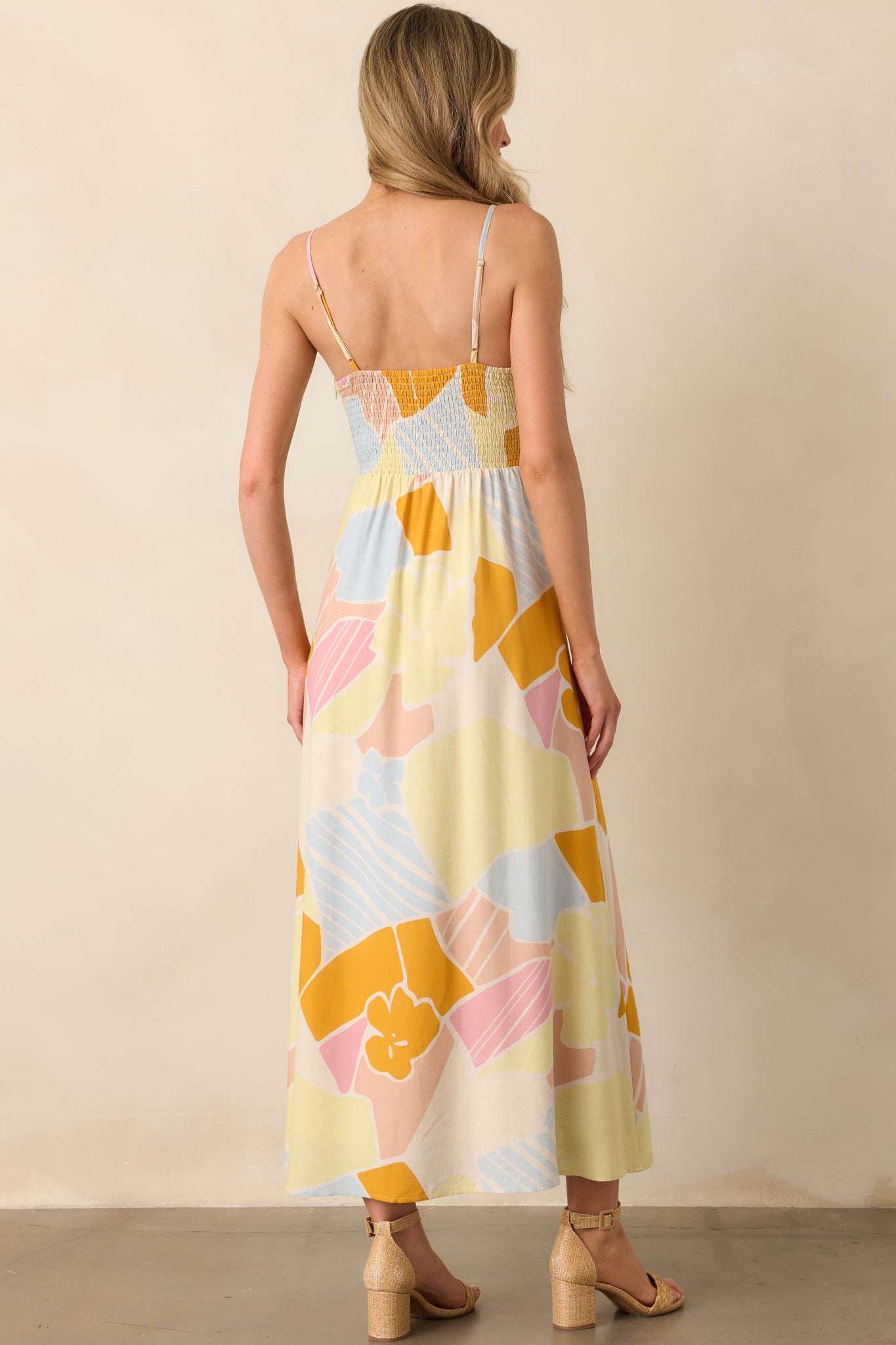 Back view of the mellow yellow maxi dress, featuring the smocked back panel and thin adjustable spaghetti straps.