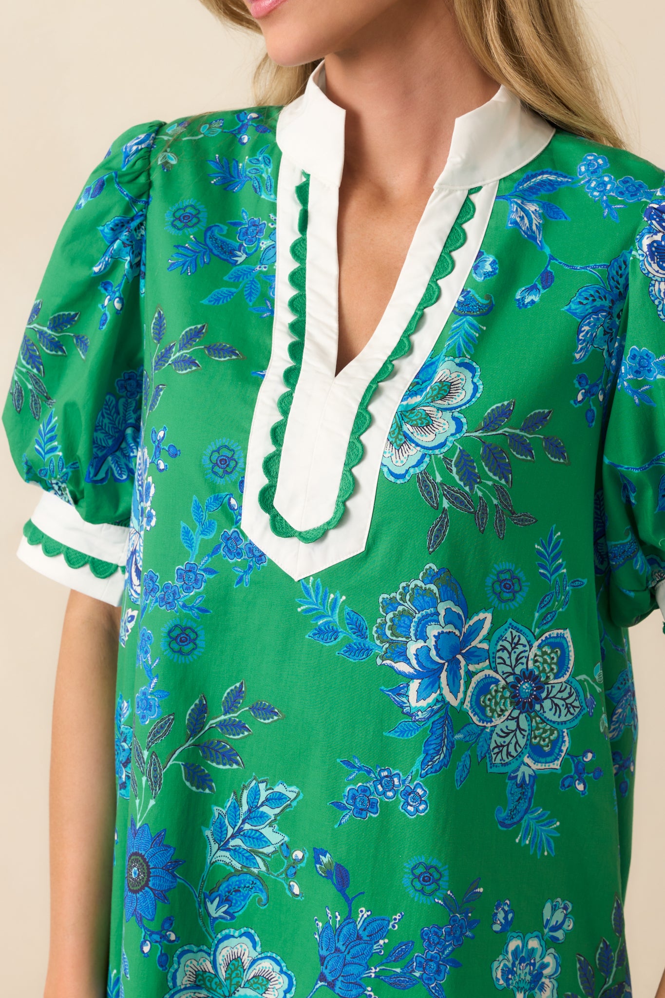 Macro image focusing on the fabric’s blue floral pattern and scalloped edge stitching, highlighting the fine detailing and color contrast.