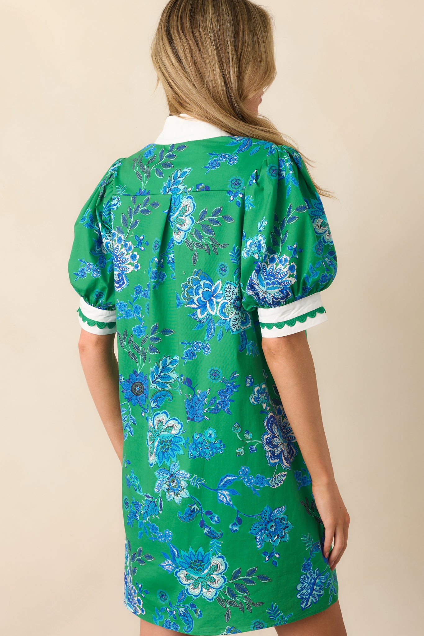 Rear view of the green mini dress showing puff sleeves, mini hem, and consistent blue floral pattern extending to the back.