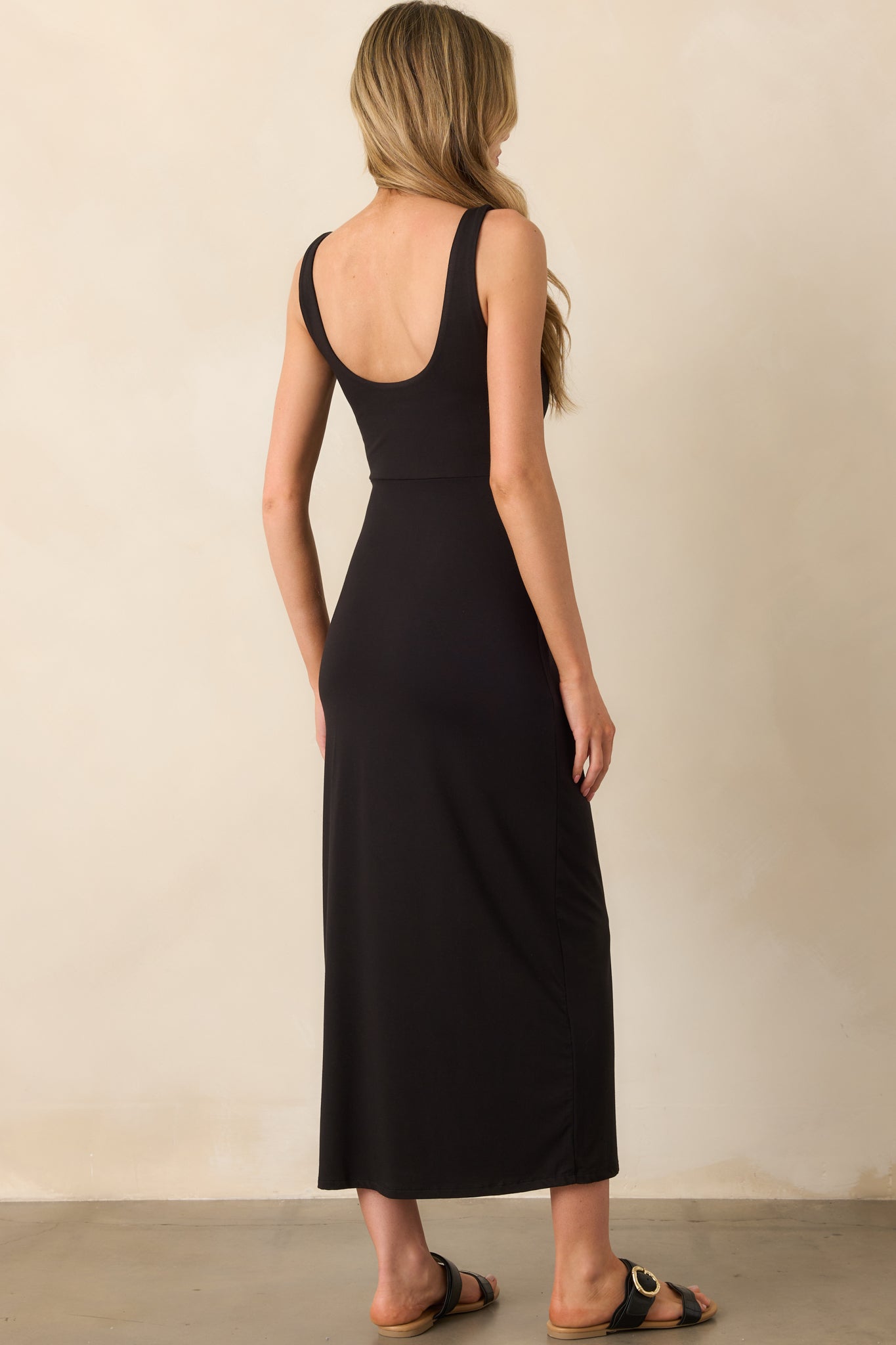 A view from behind of the black midi dress, highlighting the low scoop and smooth fit through the back.