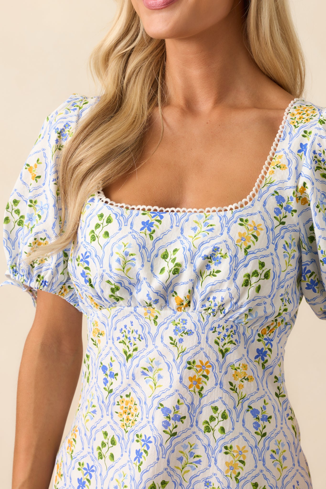 Close-up of the scallop trim along the square neckline and part of the floral pattern in soft cotton fabric.