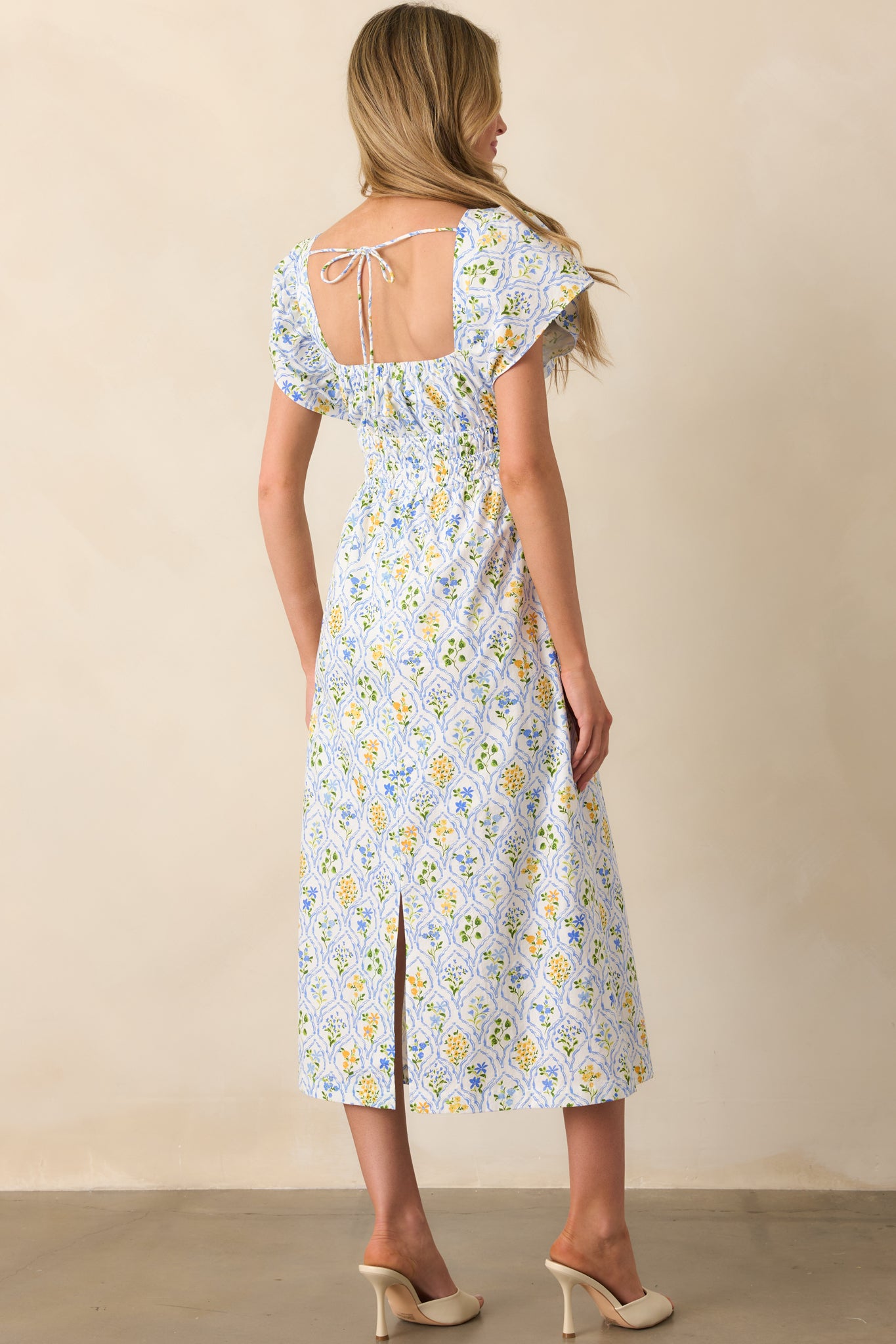 A view from behind of the midi dress, displaying the self-tie back design and flowing skirt with a subtle floral pattern.