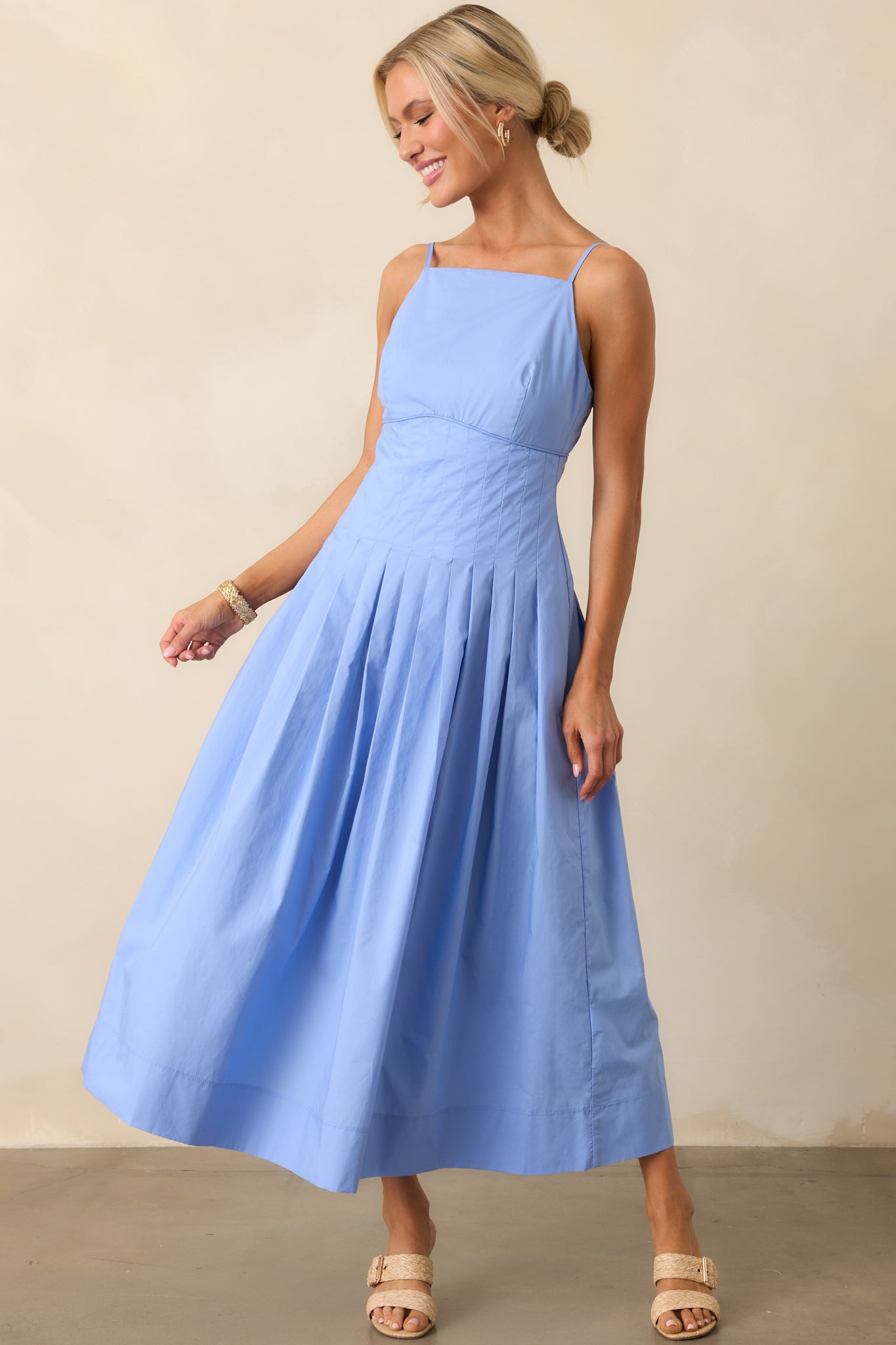 Front-facing view of jacaranda blue cotton dress showcasing the apron-style neckline and soft pleating at the skirt.