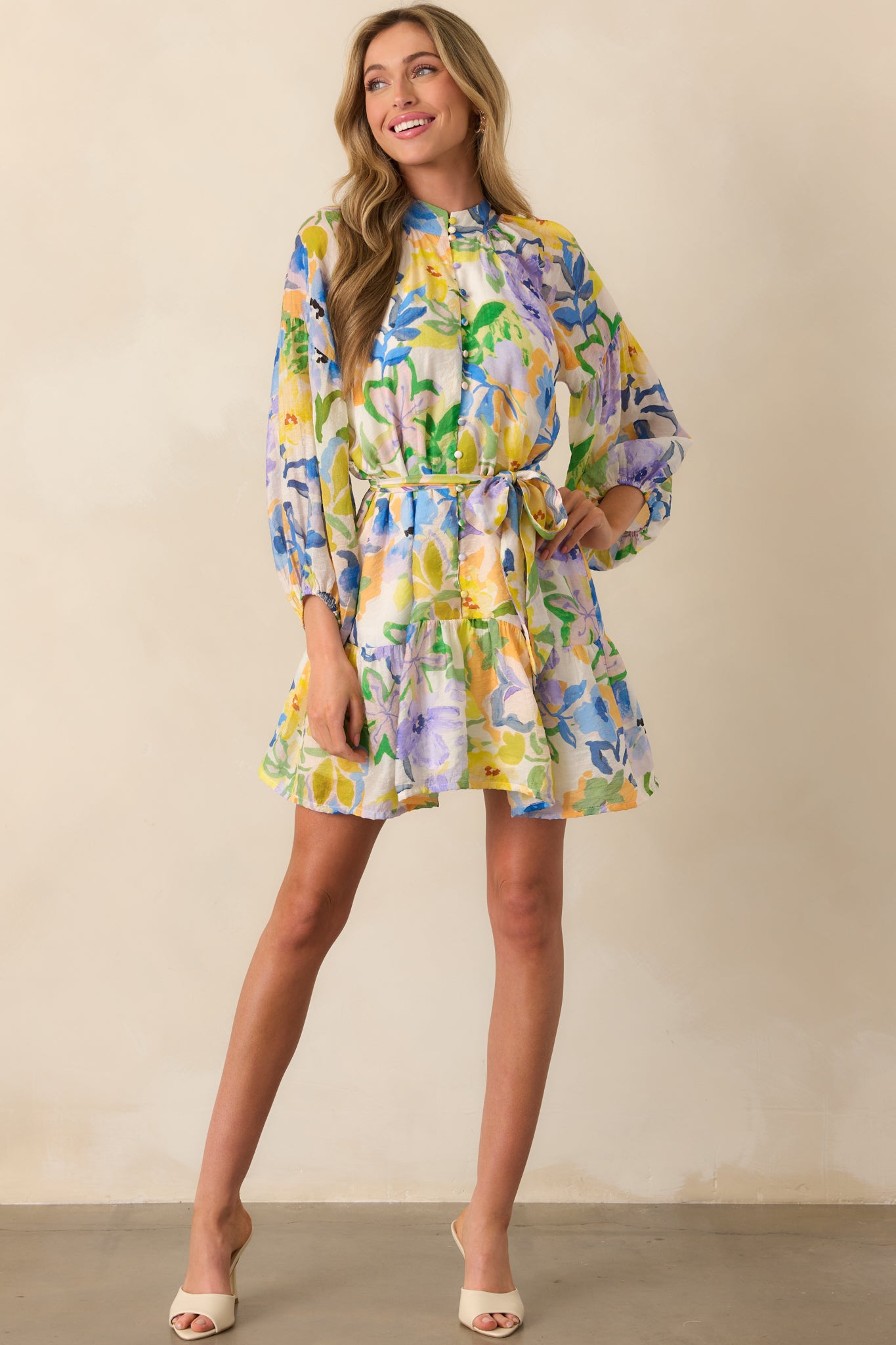 Front view of yellow mini dress with a bold multicolor floral print, mock neckline, and 3/4 length sleeves.