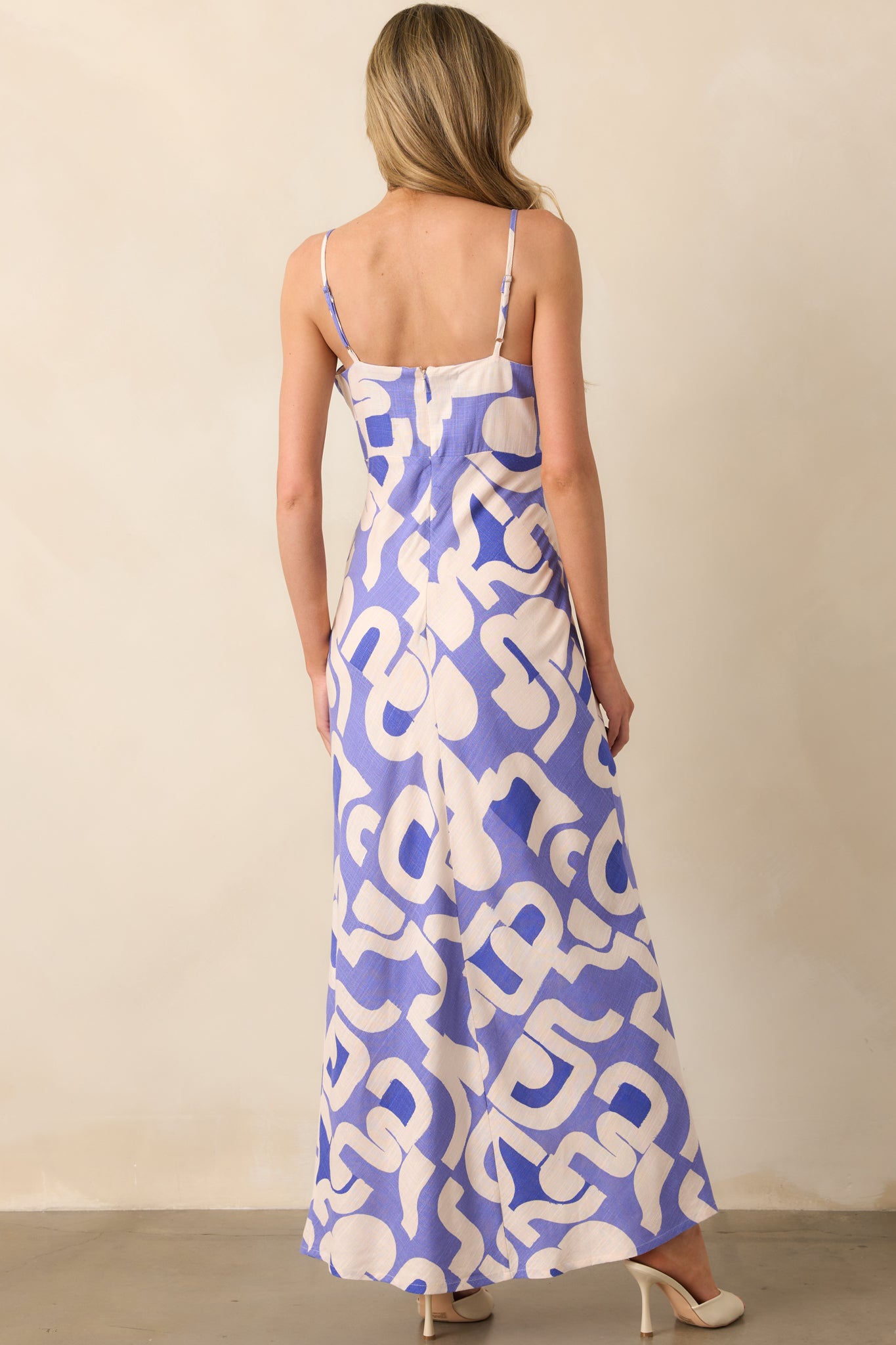 A view from behind of the dusty blue midi dress, focusing on the simple back design and adjustable spaghetti straps.