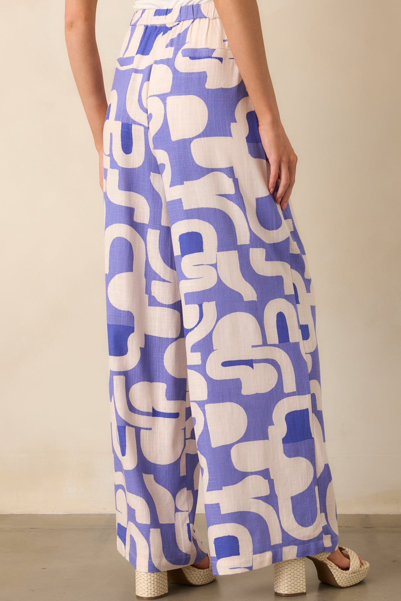 A view from behind of the dusty blue pants, showing the flowy wide leg design and elastic waistband at the back.