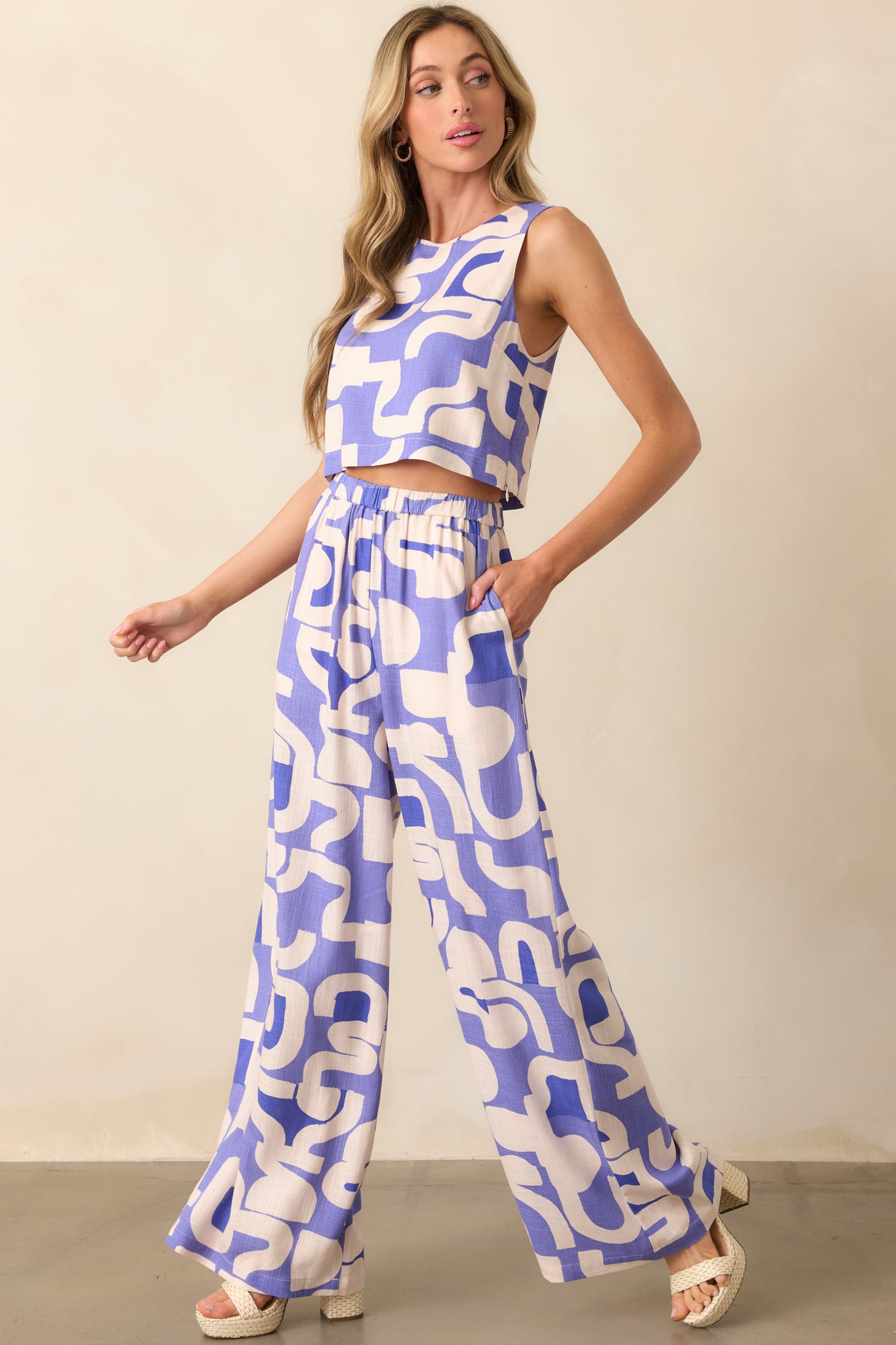 Front view of dusty blue pants featuring a multicolor geometric print, wide leg silhouette, and lightweight drape.