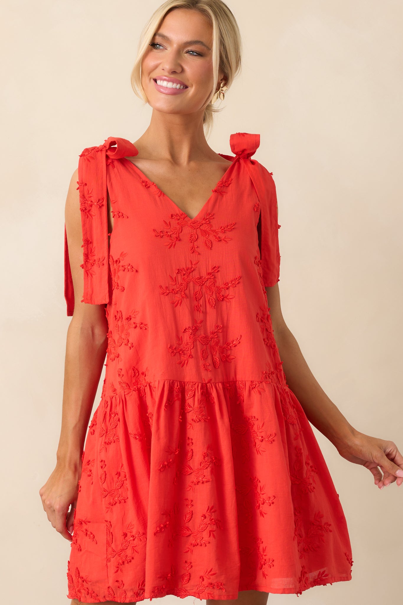Close-up of the red dress showing the placement of the functional pockets and floral embroidery detail.