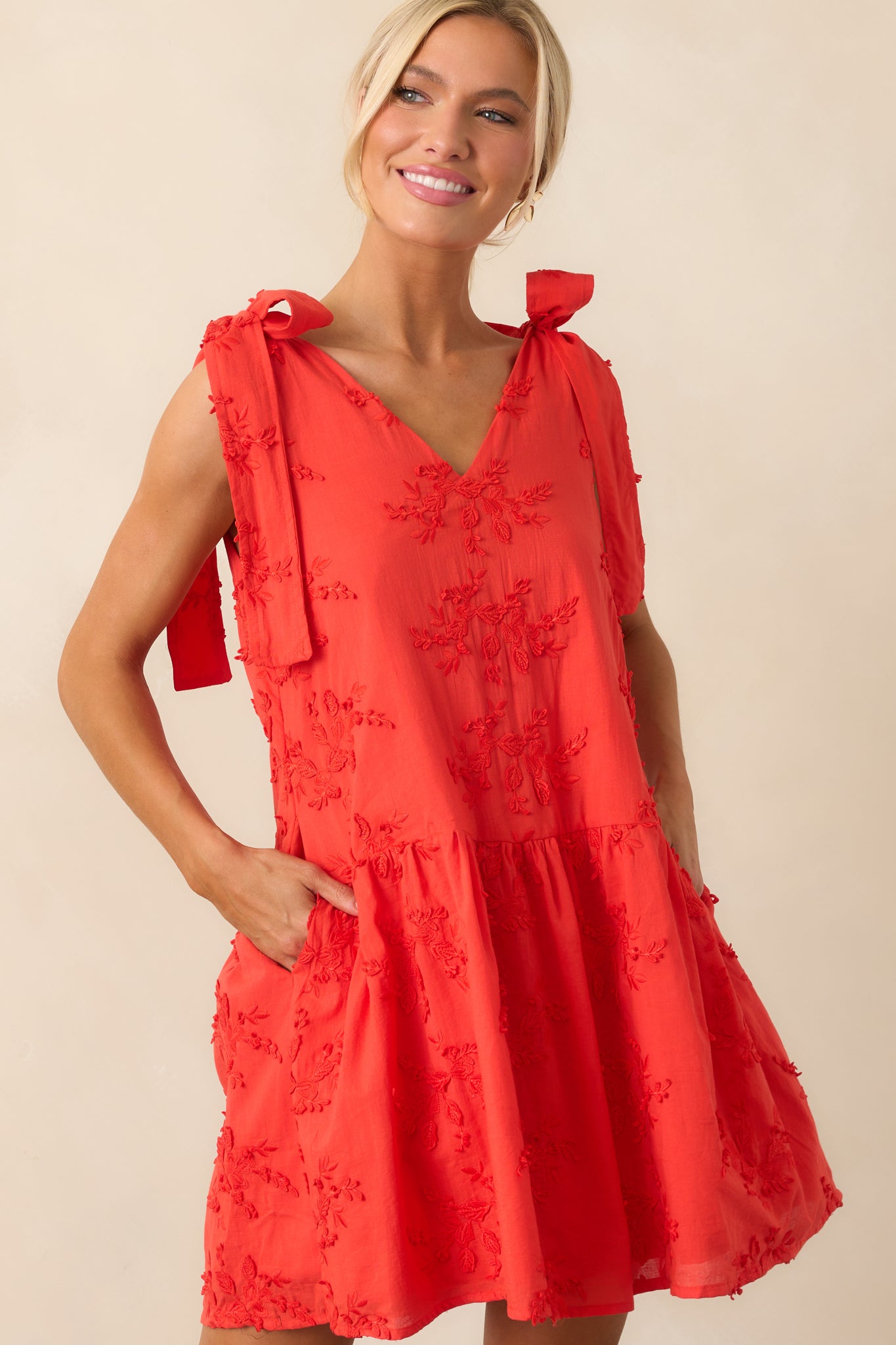 Cropped image of the red mini dress focusing on the hemline and dimensional floral embroidery.