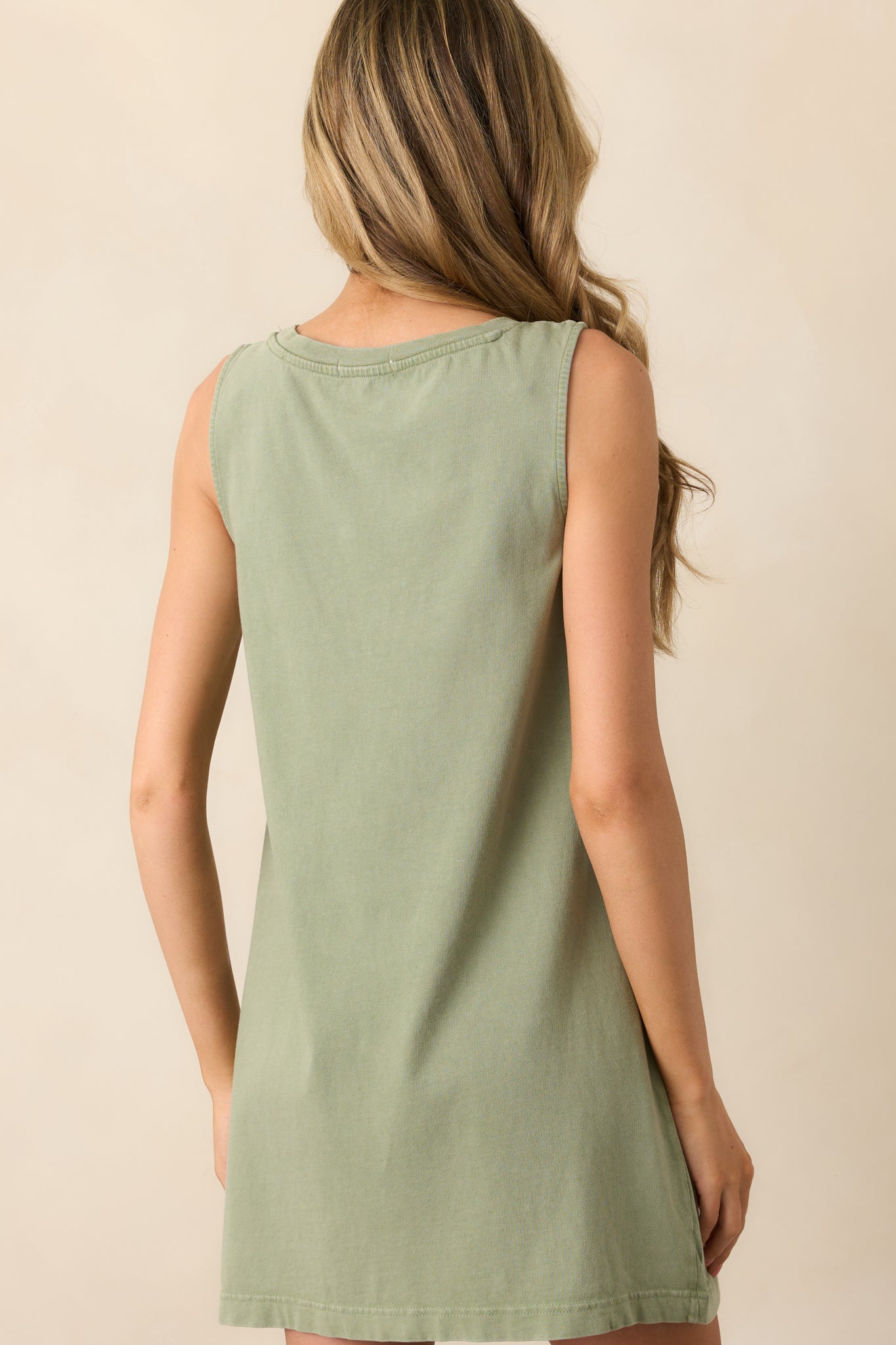 A view from behind showing the sleeveless design, relaxed drape, and clean lines of the avocado green mini dress.