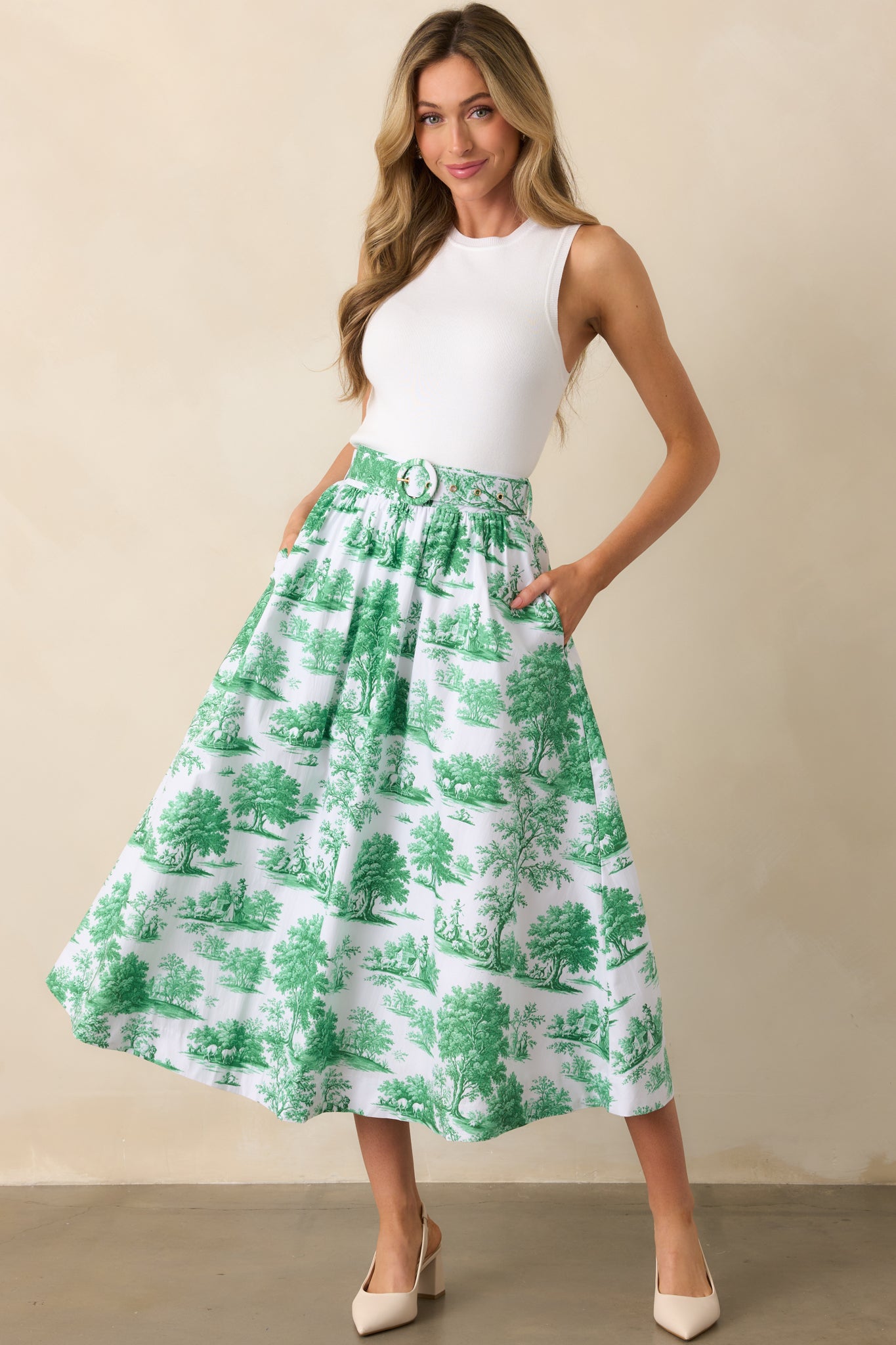A complete front view of the eden green midi skirt featuring the Prosperina toile print and matching adjustable belt neatly tied.