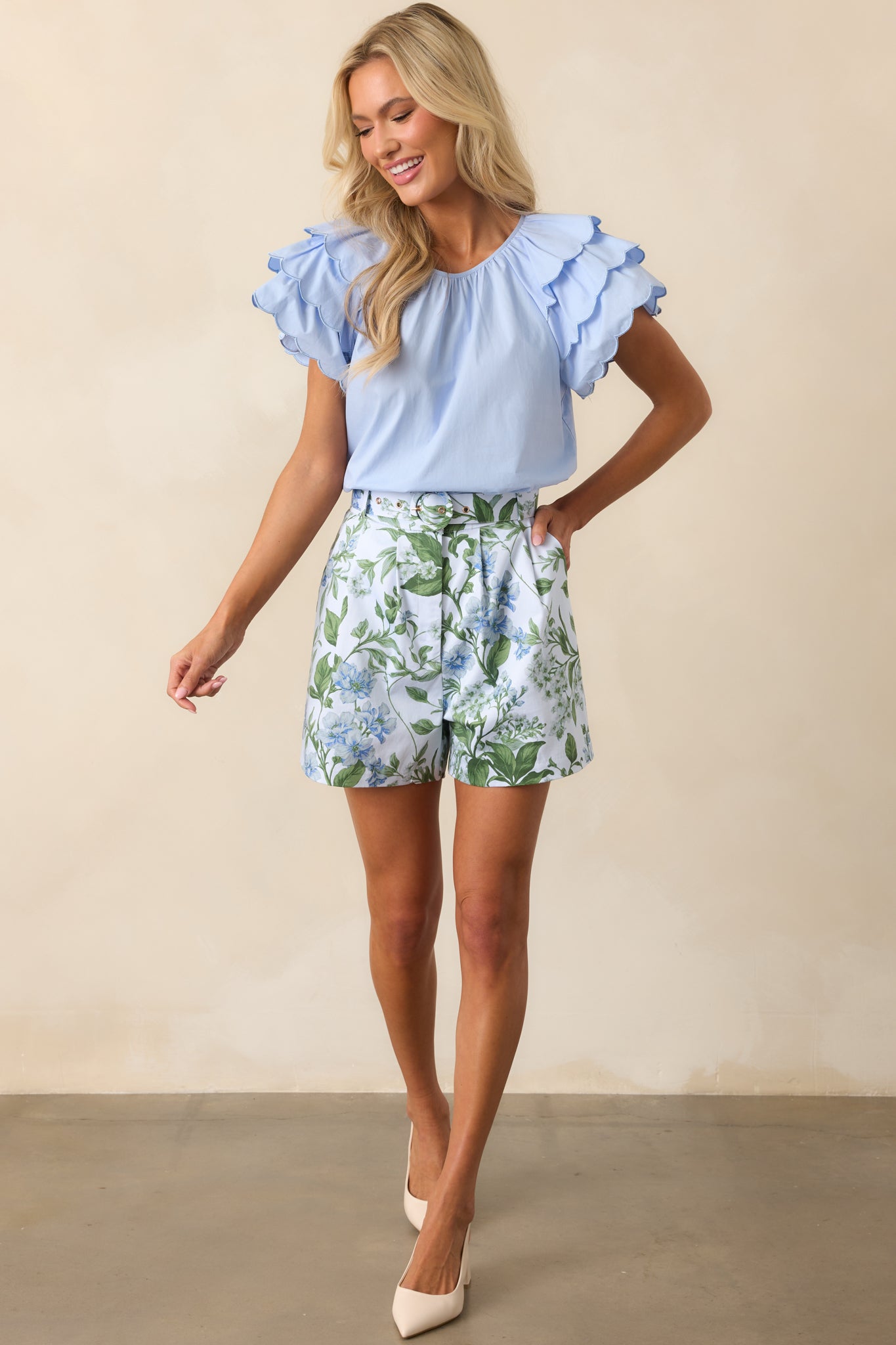 A full-length view of the blue shorts with the exclusive Prosperina Lilacs Botanical print, styled with the matching belt and a crisp tailored fit.