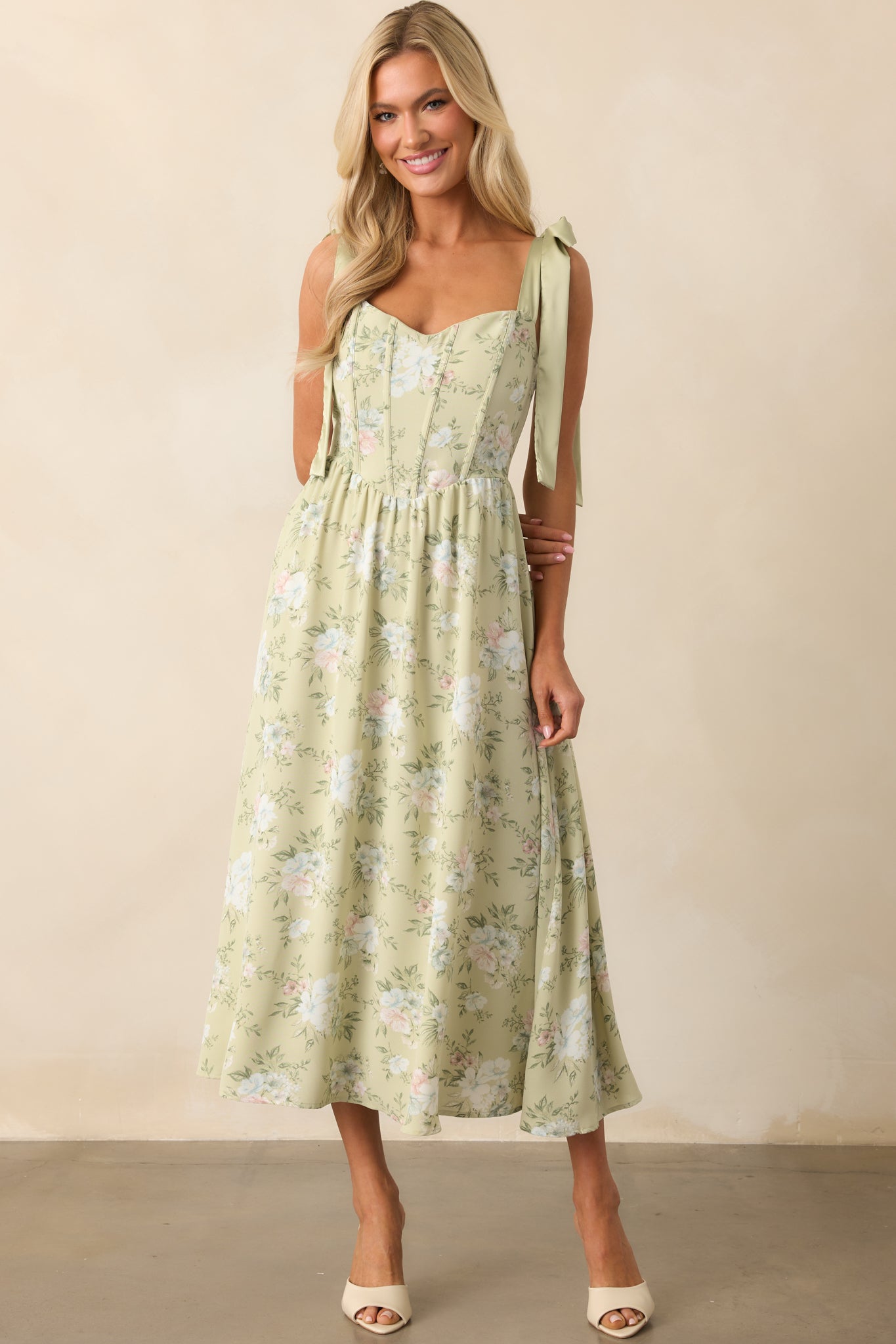 Front view of the light sage dress featuring green satin straps with decorative bows and a fitted bodice.