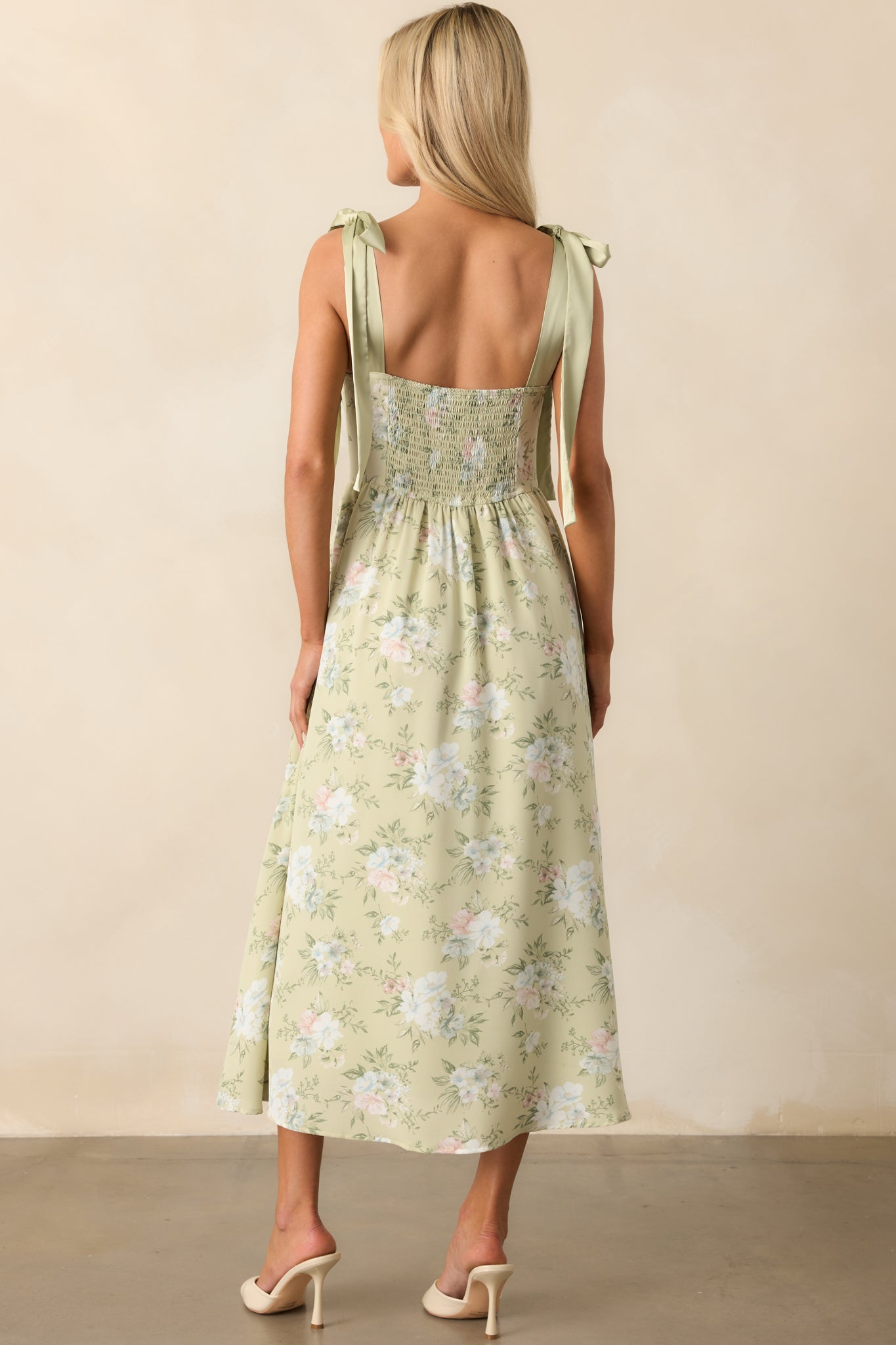 View from behind of the light sage dress displaying the smocked back panel and satin bow-tied straps.