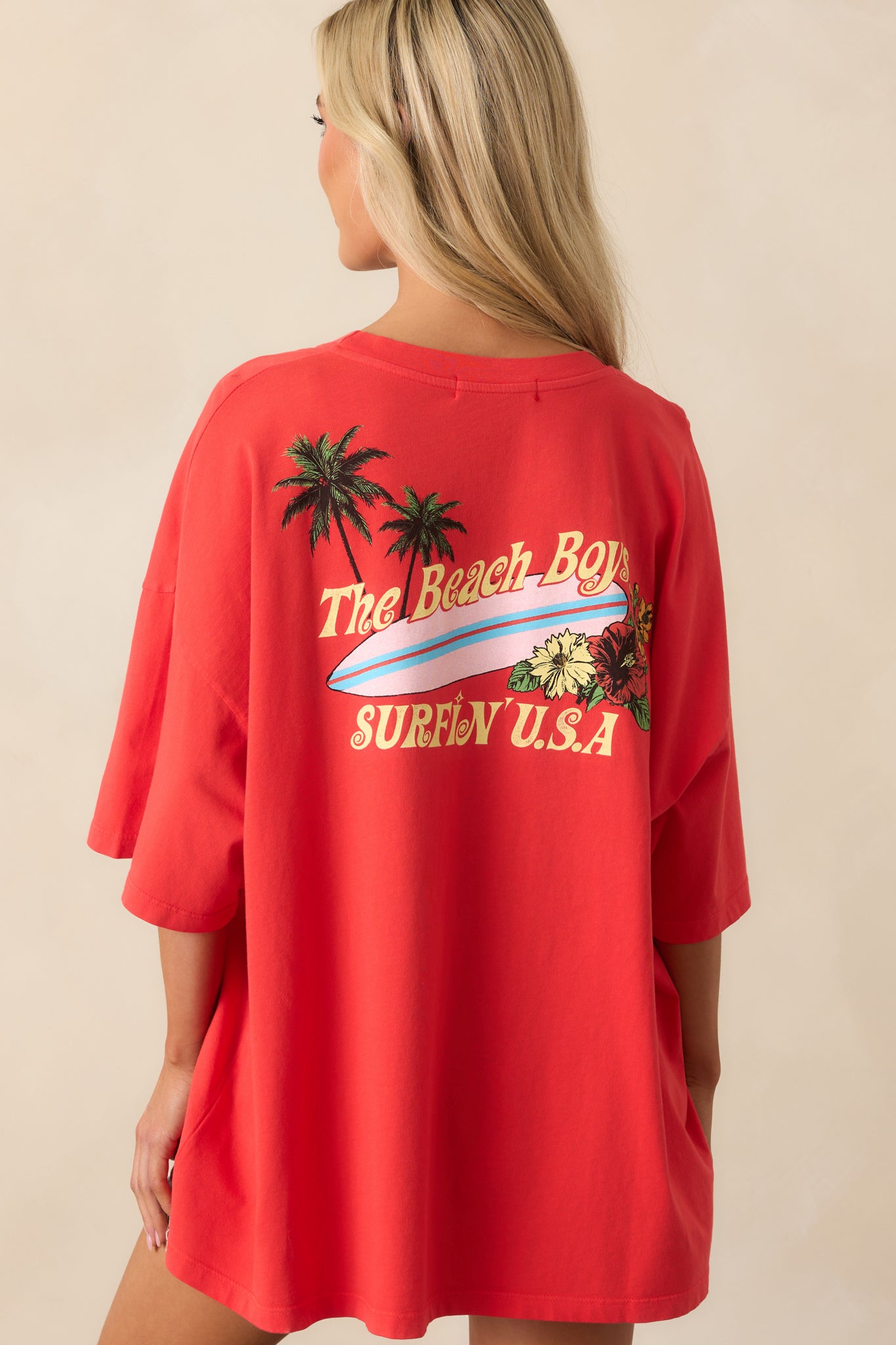 A view from behind of the red tee displaying its oversized shape and short sleeves.