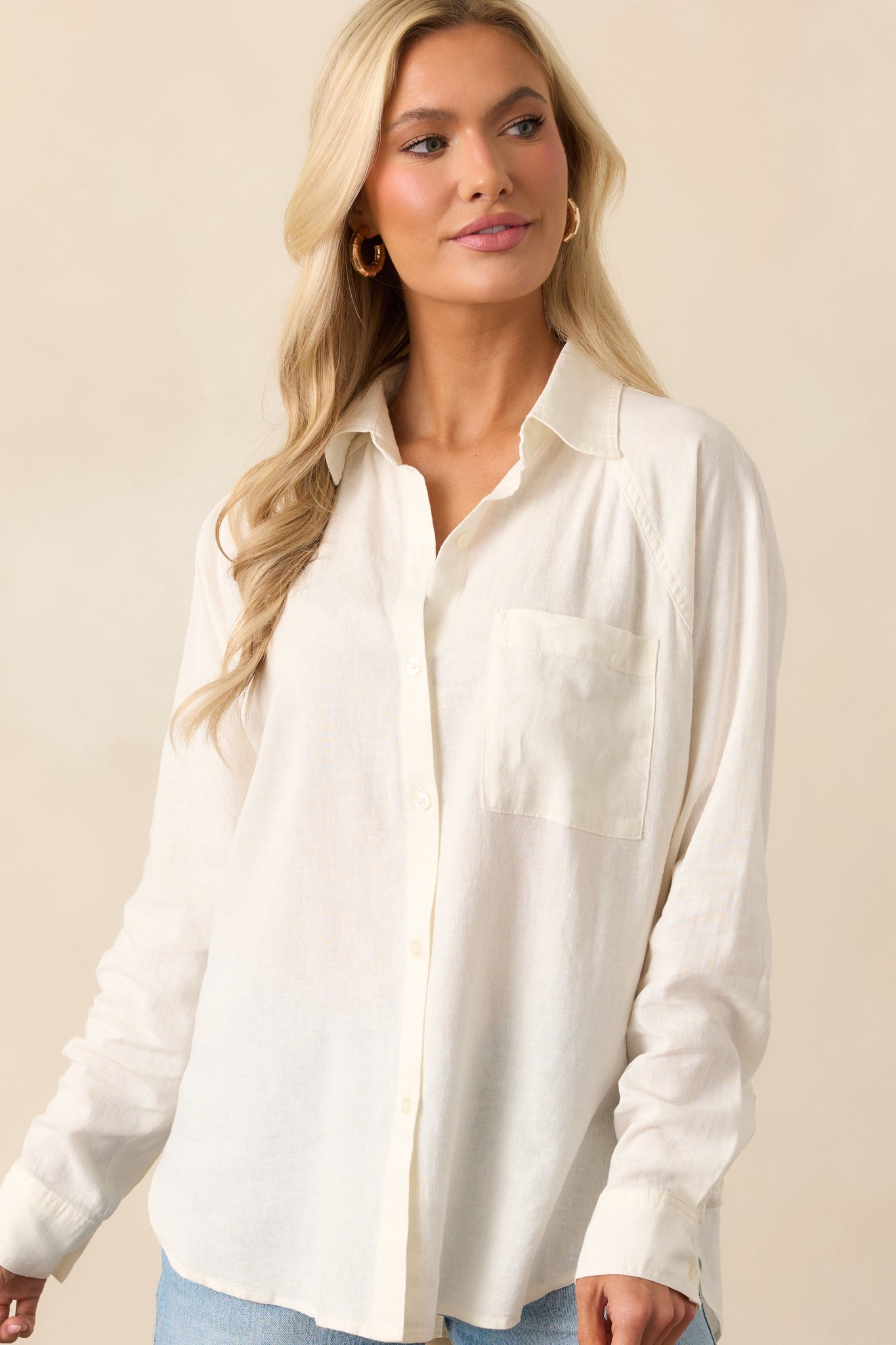 Focused image of the button front and sleeve cuff of the white top, emphasizing the shirt’s tailored elements.