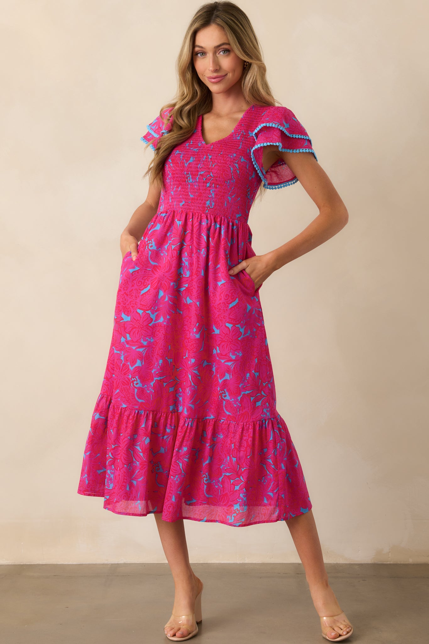 Fuchsia dress shown from the front, featuring a v-neckline, blue trim detailing, and a relaxed fit with functional pockets.