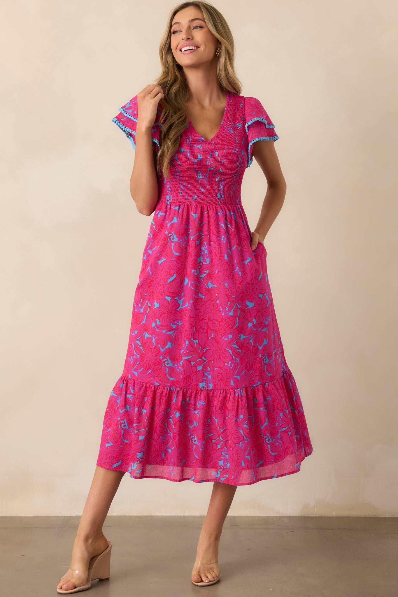 Front-facing view of the fuchsia dress, emphasizing the delicate floral print, flutter sleeves, and the blue-trimmed neckline.