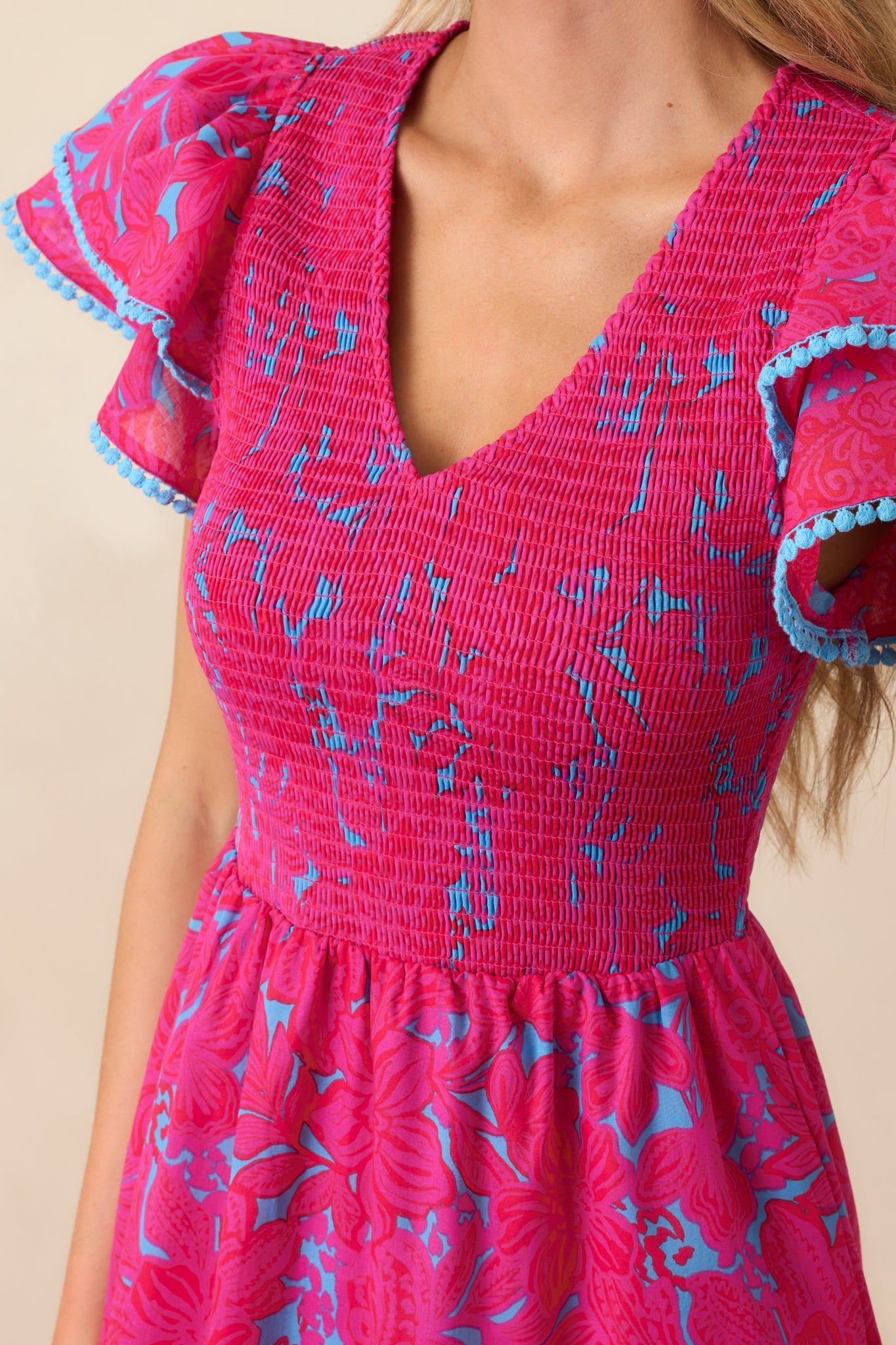 Close-up of the fully smocked bodice and v-neckline, showing the blue trim detailing and floral print texture.