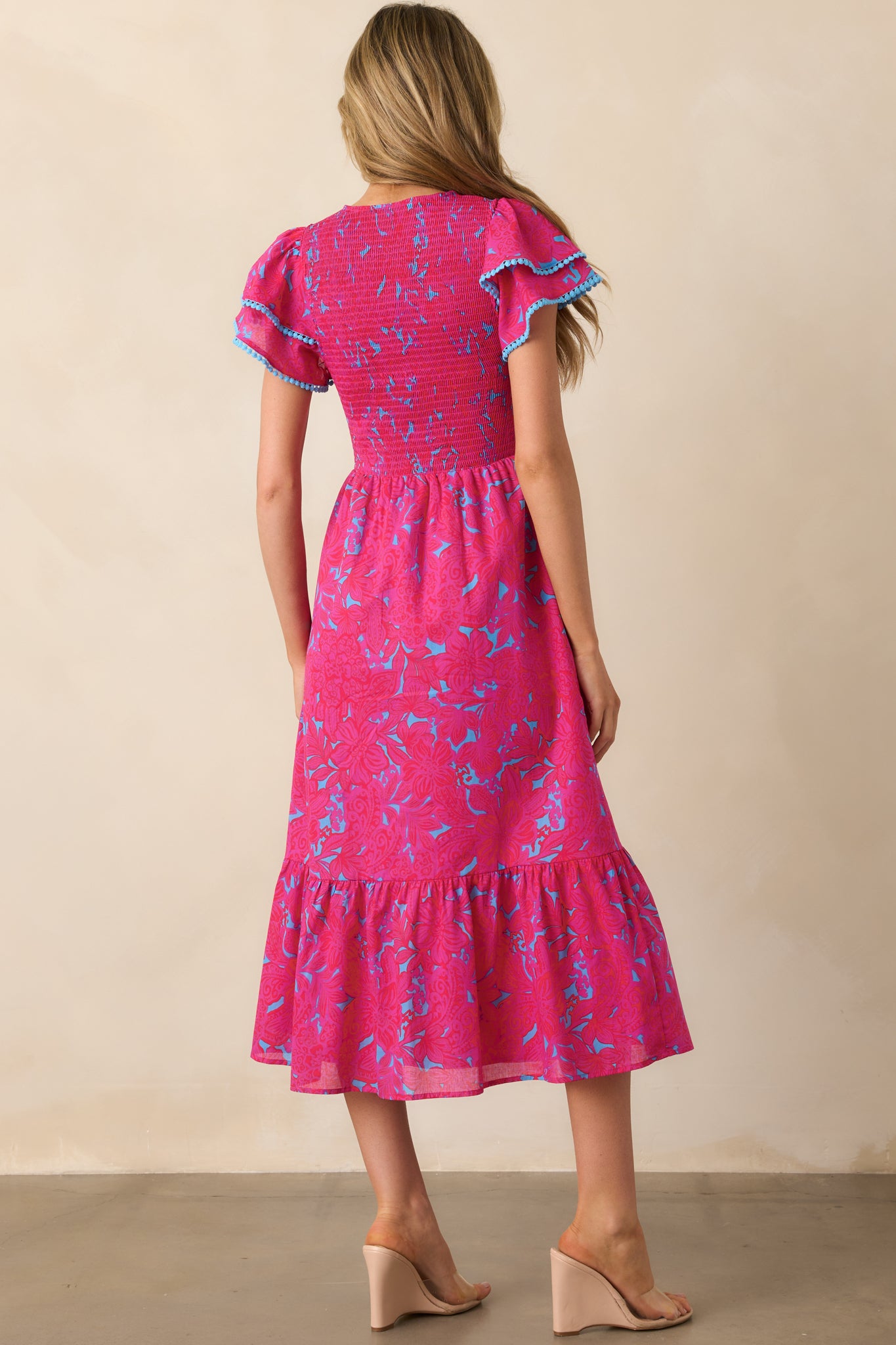 A view from behind of the fuchsia dress, focusing on the flutter sleeves and the continued floral pattern on the back.