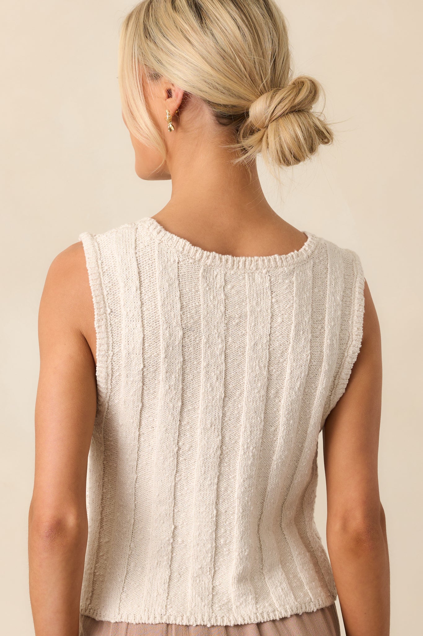 Back view of the ivory sleeveless top, showing the ribbed fabric and cropped cut with subtle hemline detail.