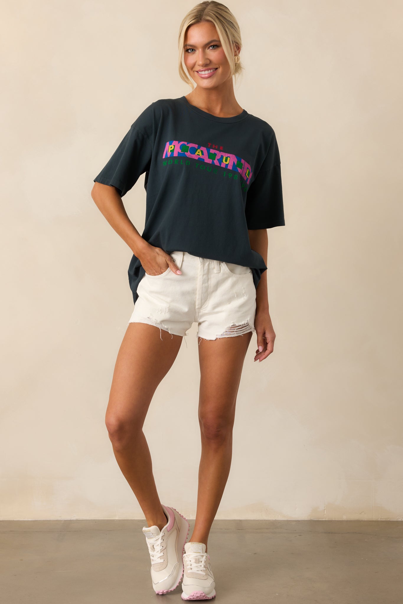 A full view of the off white denim shorts with distressed detailing throughout, a raw edge hem, and a structured 5-pocket layout.