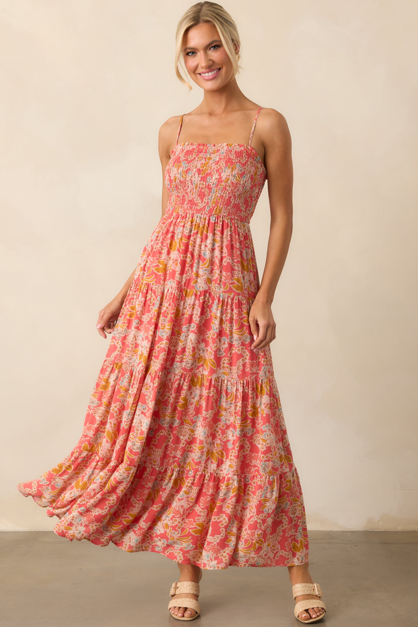 Front view of a pink coral dress with a square neckline, fully smocked bust, and adjustable spaghetti straps.