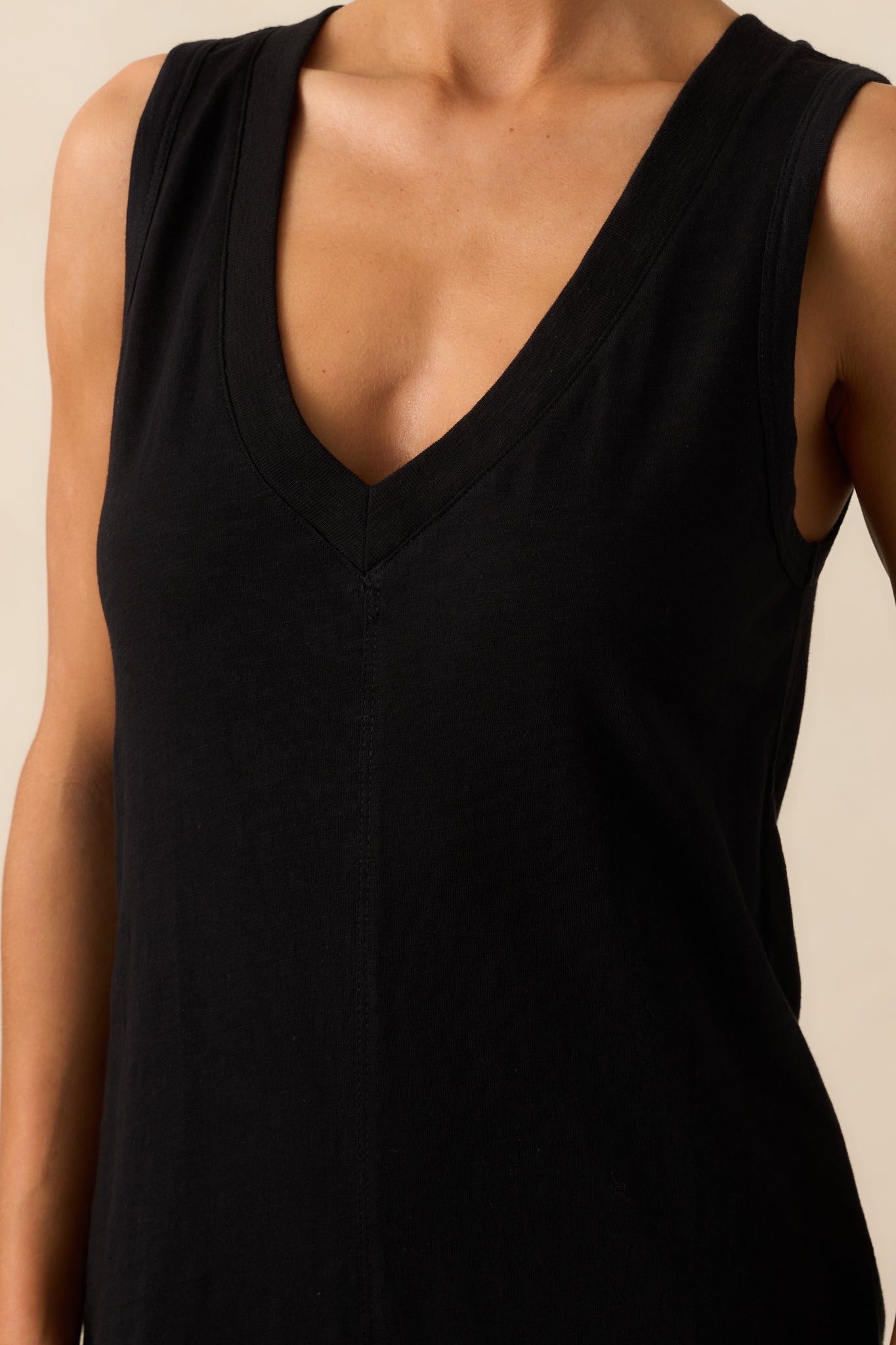 A close-up shot of the V-neckline and fabric texture of the black cotton dress, showing stitching and material weight.
