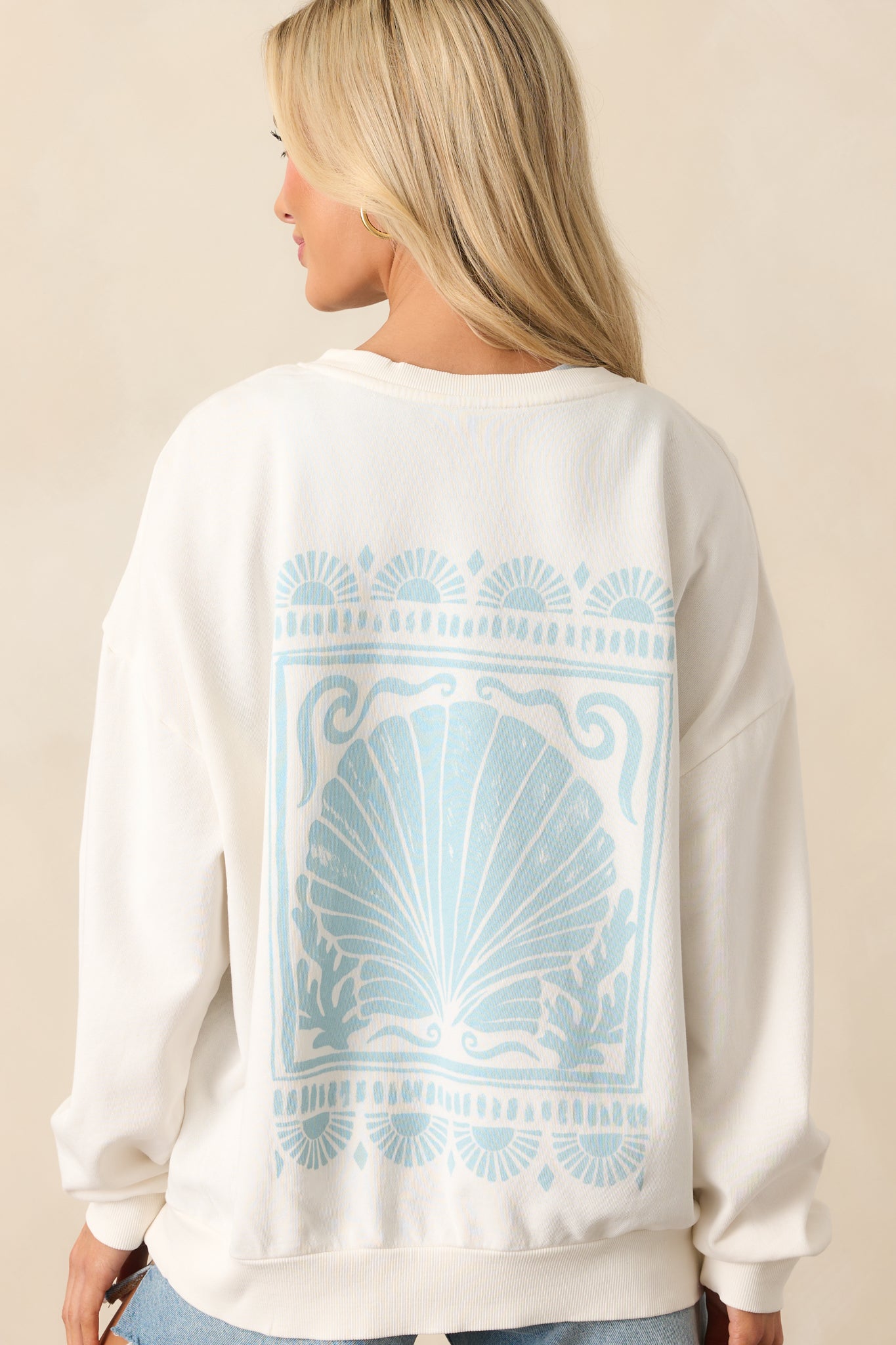 A view from behind of the sea salt ivory sweatshirt, displaying the oversized ocean-themed graphic across the upper back.