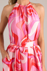 Close up view of this jumpsuit that features a high haltered neckline with a braided self tie detail, open back, adjustable belt, pockets at the thigh, and a wide leg.
