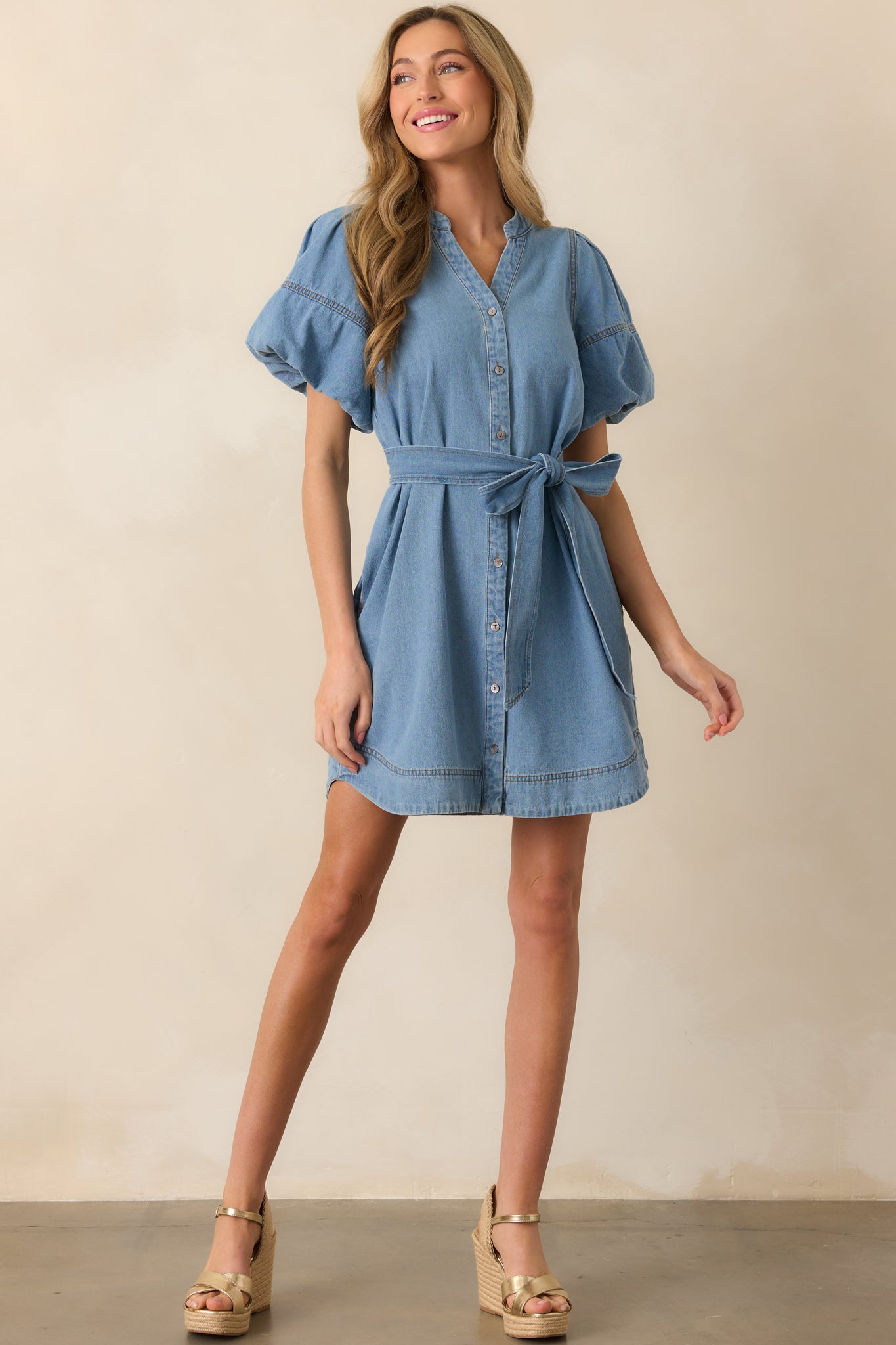 Light wash mini dress shown in a front-facing full body view, featuring a button front design and adjustable self-tie belt.