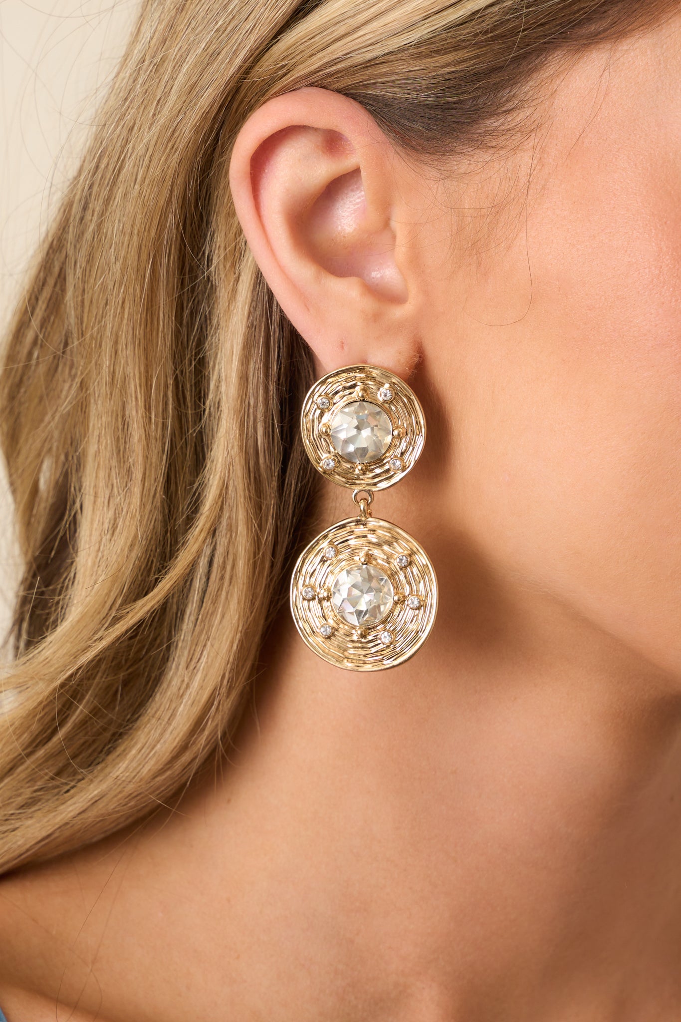 A close-up detail of the earring’s circular rhinestone arrangement, showing the intricate placement of each stone and polished metal finish.